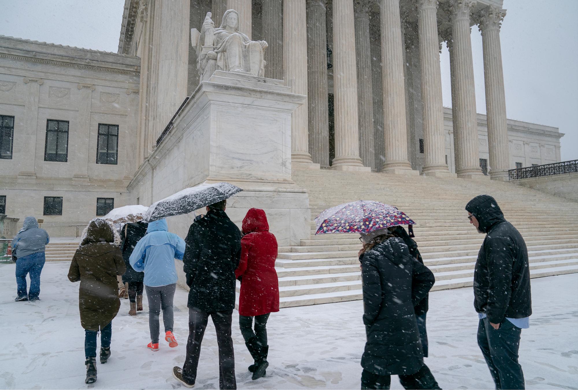 Los visitantes ingresan a la Corte Suprema cuando una tormenta invernal de nieve golpea la capital de la nación, lo que hace que las carreteras sean peligrosas y que cierren la mayoría de las oficinas federales y los principales distritos escolares públicos, en Capitol Hill en Washington.