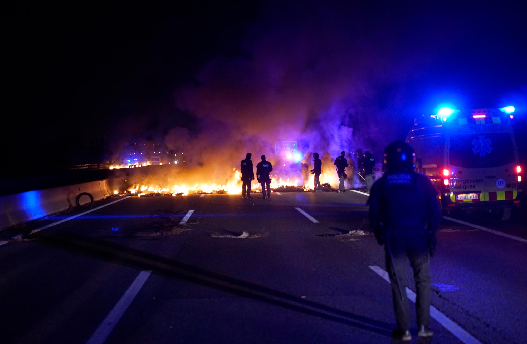 Los oficiales de policía intentan eliminar los neumáticos quemados, establecidos por los manifestantes para bloquear una carretera en protesta por el encarcelamiento de líderes políticos independentistas durante una huelga general en Cataluña, España. 