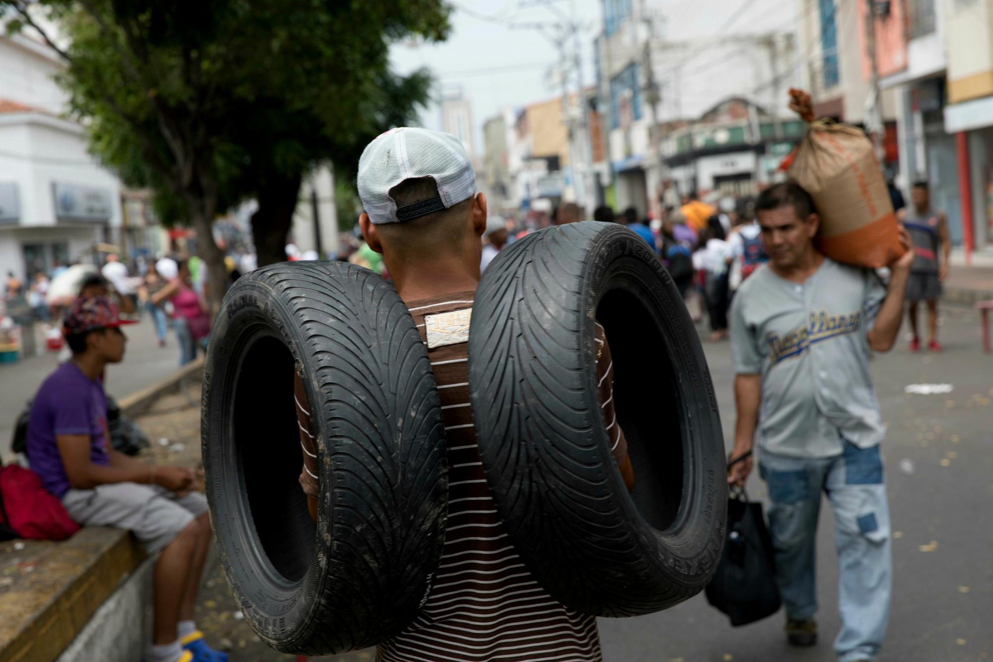 Un hombre lleva un par de llantas que compró en Cúcuta, Colombia, cuando regresa a San Antonio del Táchira, Venezuela, en la frontera con Colombia. 
