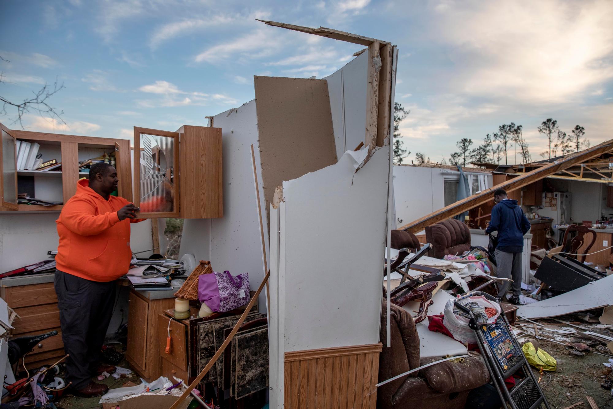 Granadas Baker, izquierda, y su hijo Granadas Jr. 18, derecha, recuperan artículos personales de la casa dañada donde sobrevivieron a un tornado el día anterior en Beauregard, Alabama, el lunes 4 de marzo de 2019.