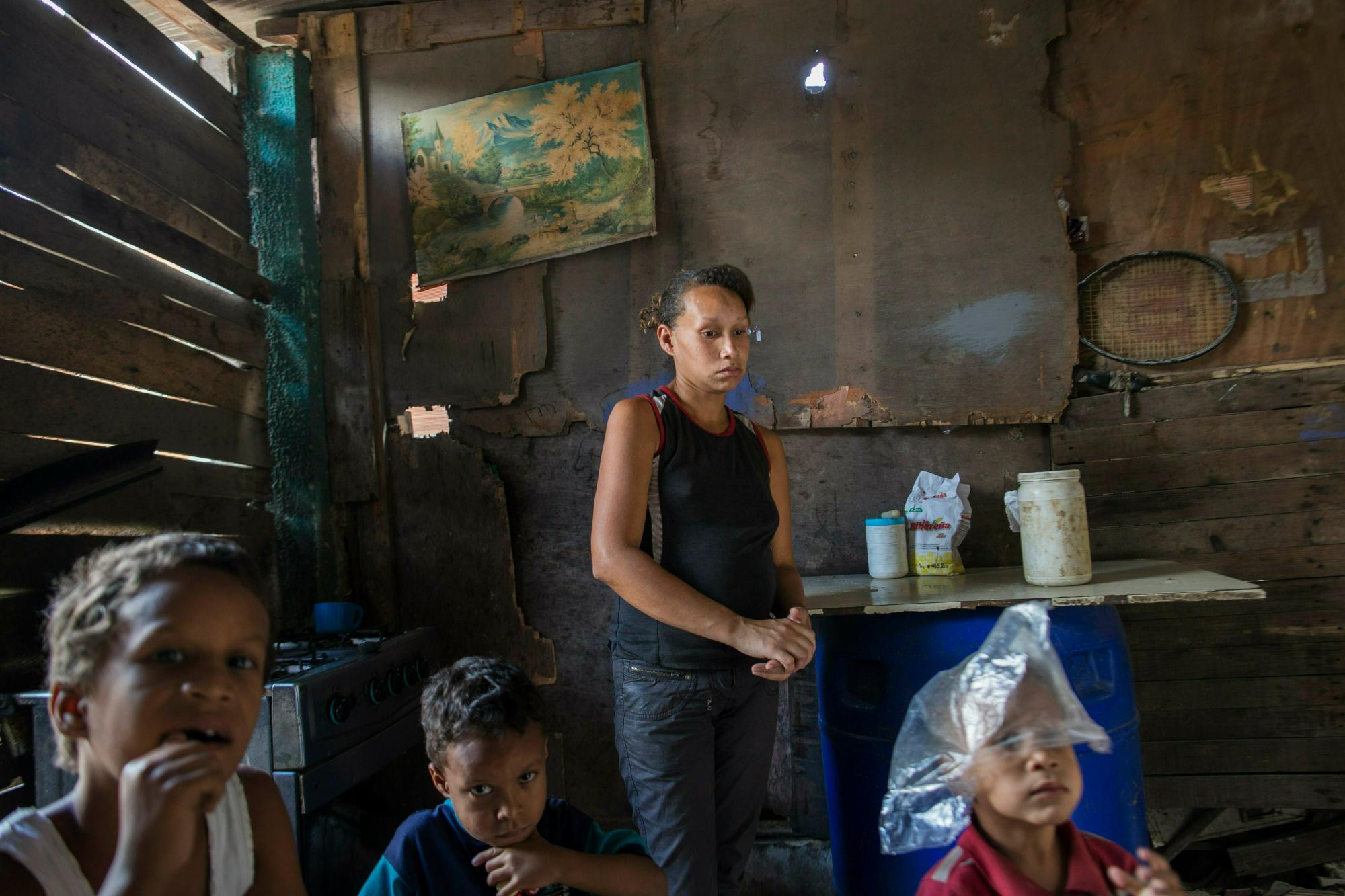 En esta foto del 14 de febrero de 2019, Francis se para en la sala de estar con sus hijos Moises, de 8 años, desde la izquierda, Joyker, de 5 años, y Eduardo, de 4, en el barrio de Petare, en Caracas, Venezuela. La mayoría de los venezolanos culpan a Nicolás Maduro por la crisis económica.