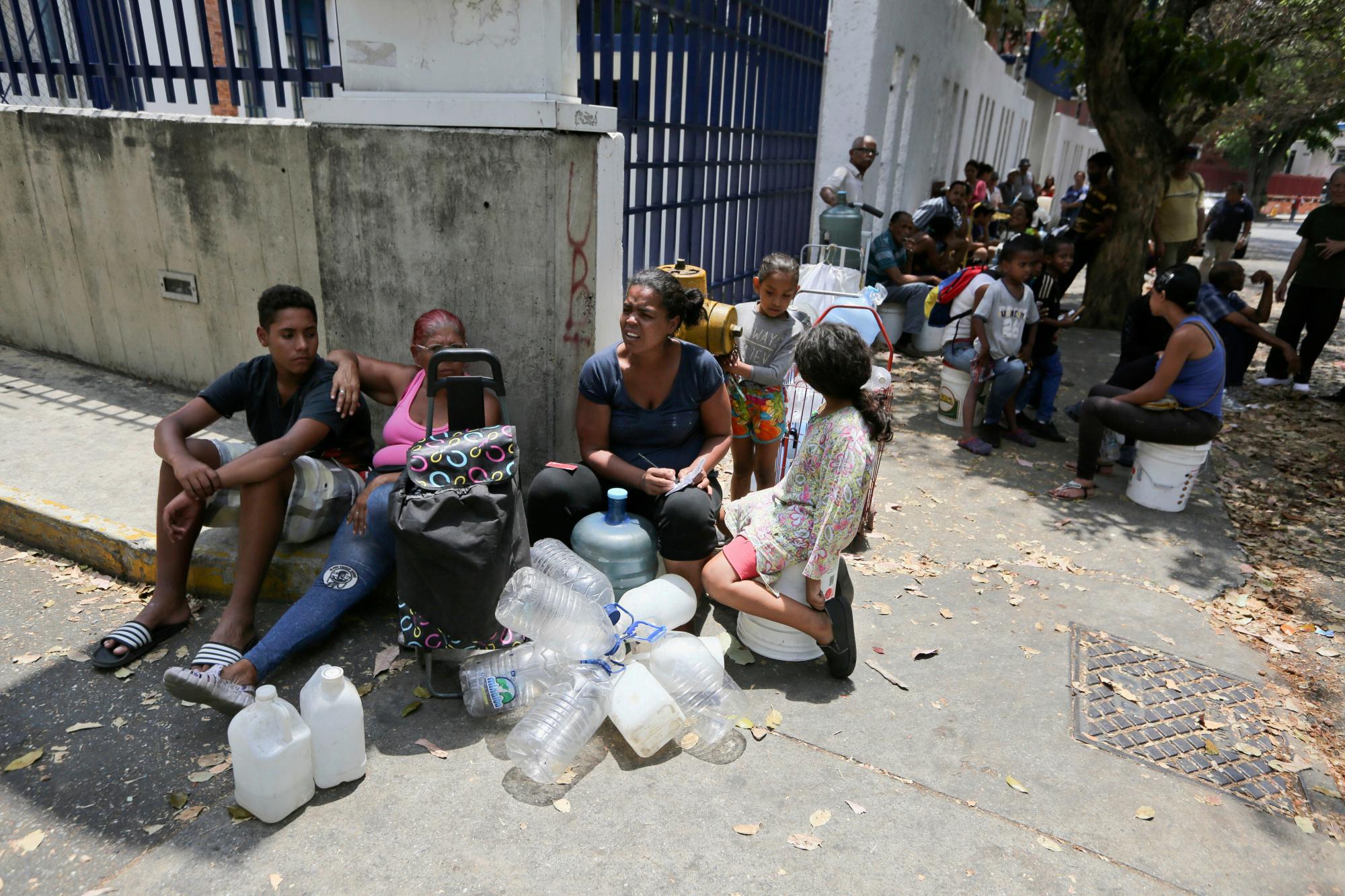 Algunas personas esperan su turno para llenar contenedores con agua de una fuente pública en Caracas, el miércoles 13 de marzo de 2019.