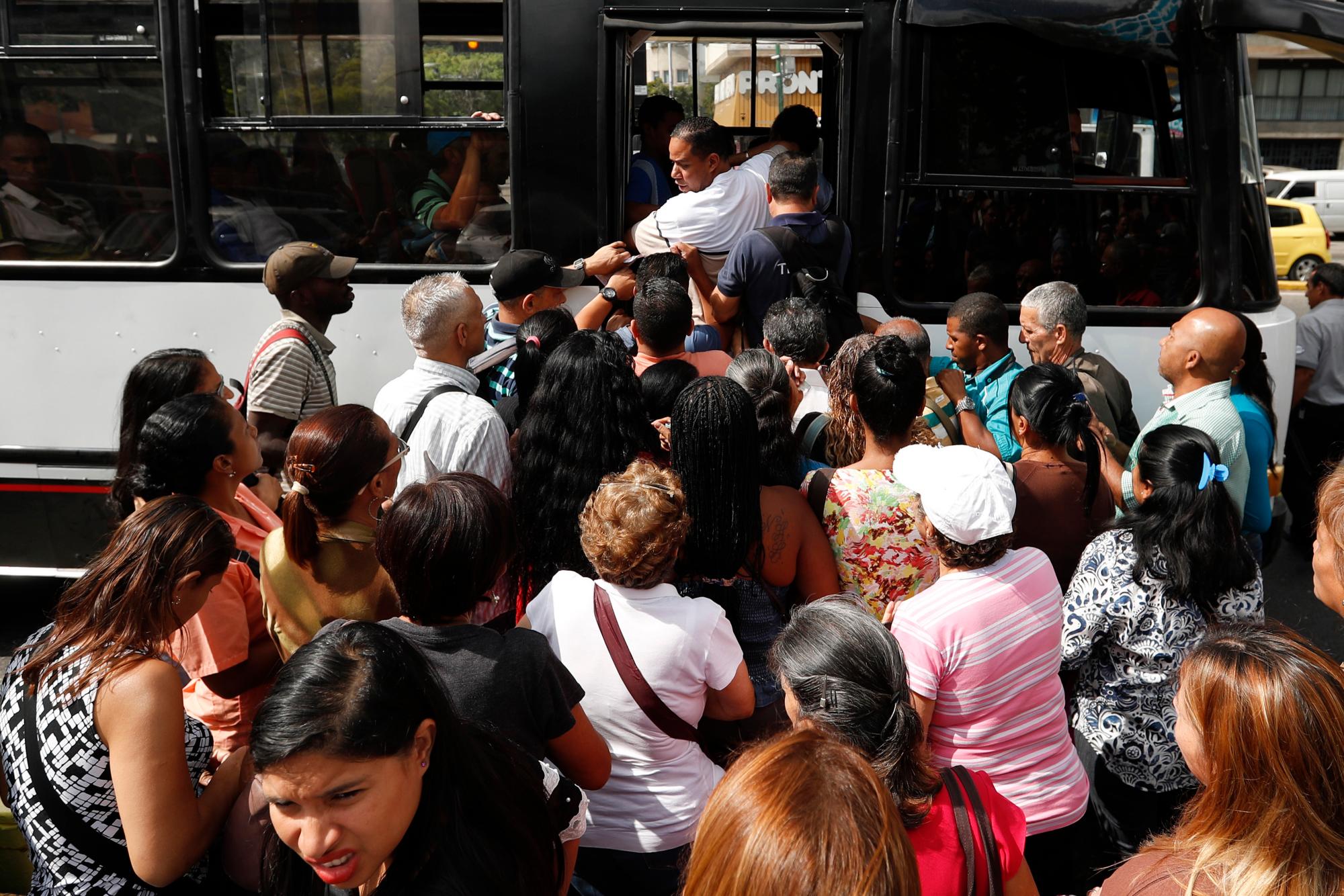 Los pasajeros se apresuran para abordar un autobús en Caracas, Venezuela, el jueves 14 de marzo de 2019. 