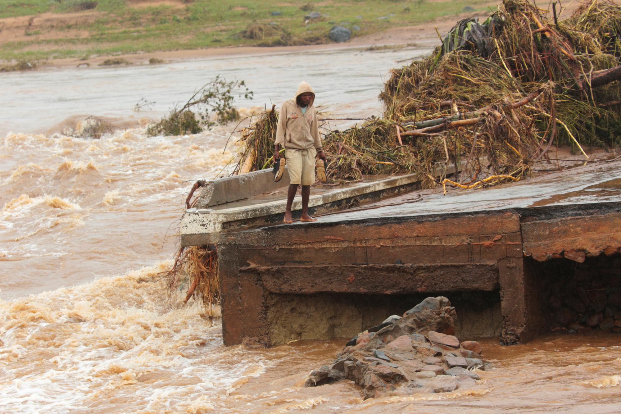 Un hombre se para en el borde de un puente derrumbado en Chimanimani, a unos 600 kilómetros al sureste de Harare, Zimbabwe, el lunes 18 de marzo de 2019.