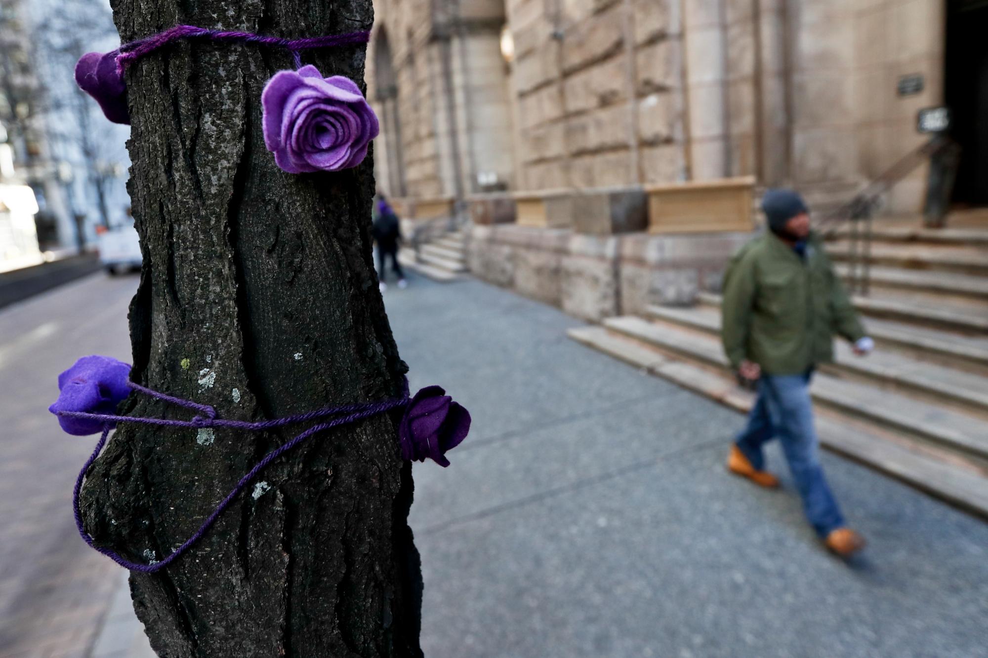 Las rosas de tela púrpura adornan los árboles a lo largo de Grant St., mientras la gente camina frente al Palacio de Justicia del Condado de Allegheny el primer día del juicio para Michael Rosfeld, un ex oficial de policía en East Pittsburgh, PA., el martes 19 de marzo de 2019 en Pittsburgh.