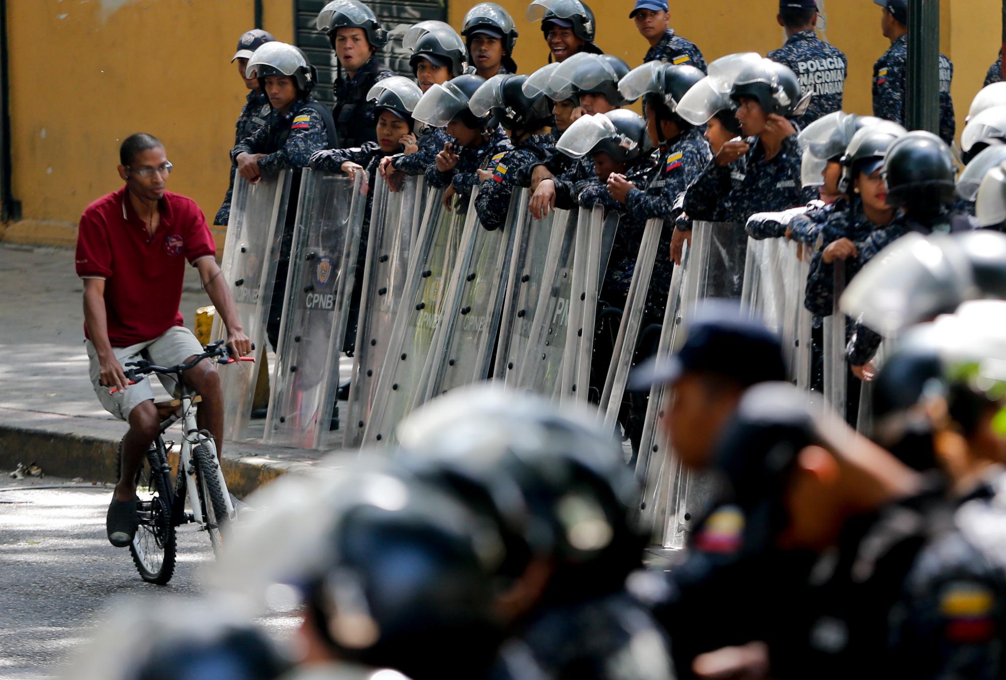 La policía se mantiene en guardia ante una marcha de una coalición de partidos de oposición que están solicitando a los legisladores de una agencia la aplicación de la ley en Caracas, Venezuela, el martes, marzo 19, 2019.