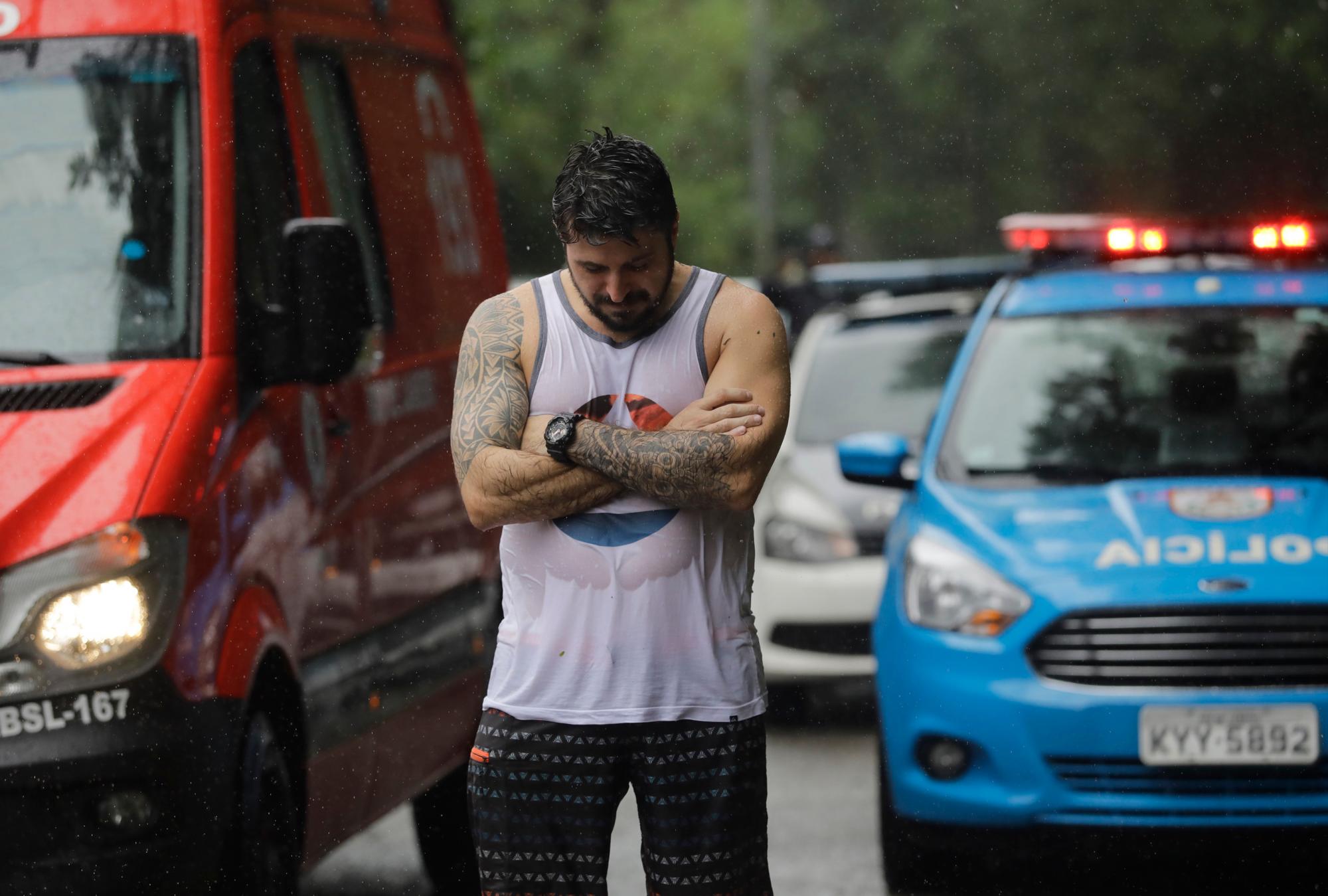 Un amigo de una persona desaparecida observa cerca en un área donde las fuertes lluvias causaron un deslizamiento de tierra enterrando a la mitad varios vehículos y arrancaron árboles en Río de Janeiro, Brasil.