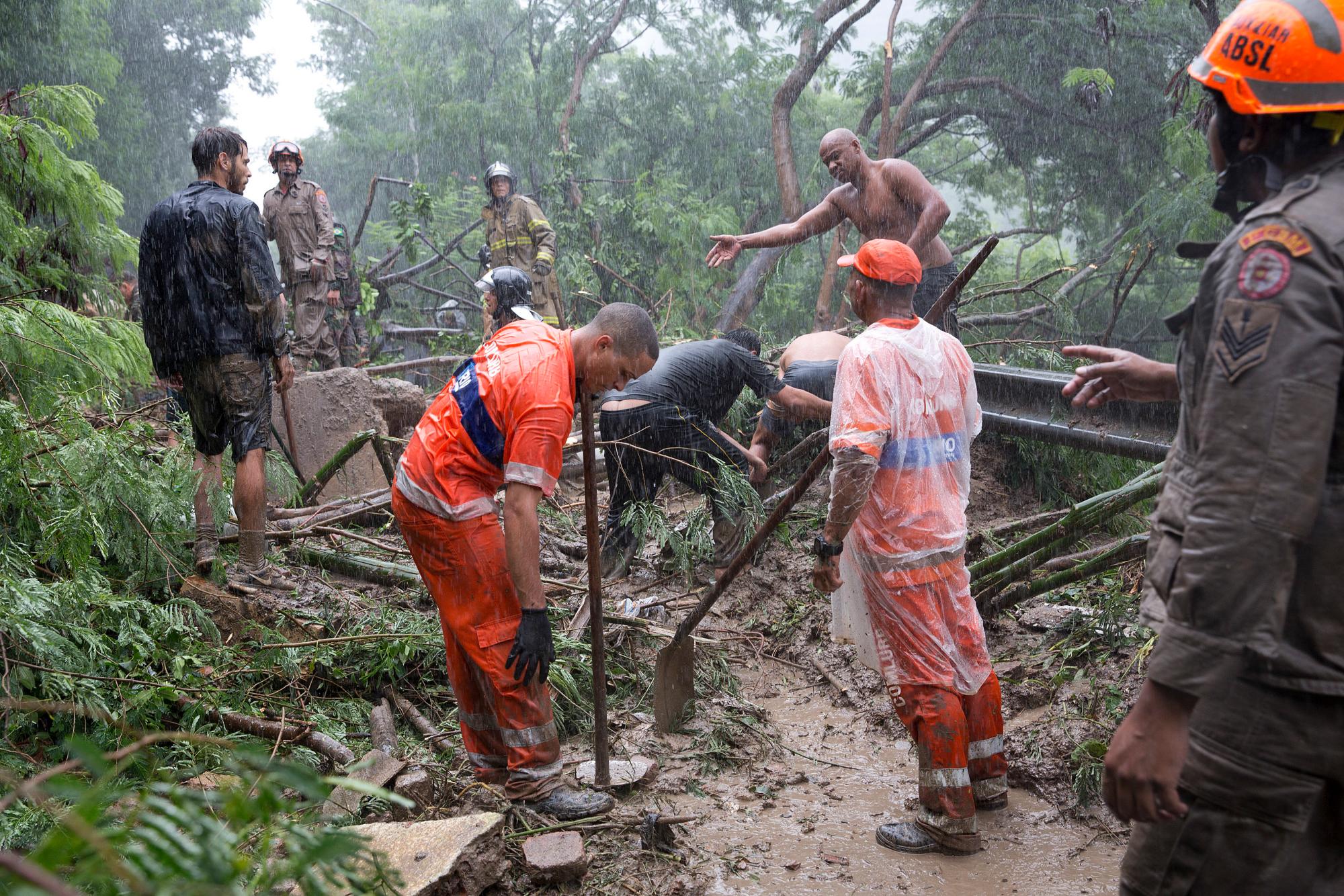 Rescatistas y residentes buscan sobrevivientes en un sitio donde los vehículos fueron enterrados en lodo y arrancados de árboles después de fuertes lluvias en Río de Janeiro, Brasil, el martes 9 de abril de 2019. 