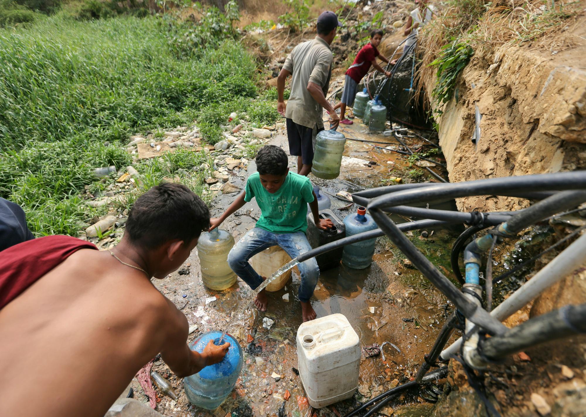 Personas recolectan agua dulce de tuberías rotas cerca de una barriada en Maracaibo, Venezuela, el sábado 13 de abril de 2019. Desde que se produjo una falla eléctrica masiva el 7 de marzo, la nación ha sufrido apagones casi todos los días y una falla en servicios críticos como agua corriente y transporte público.