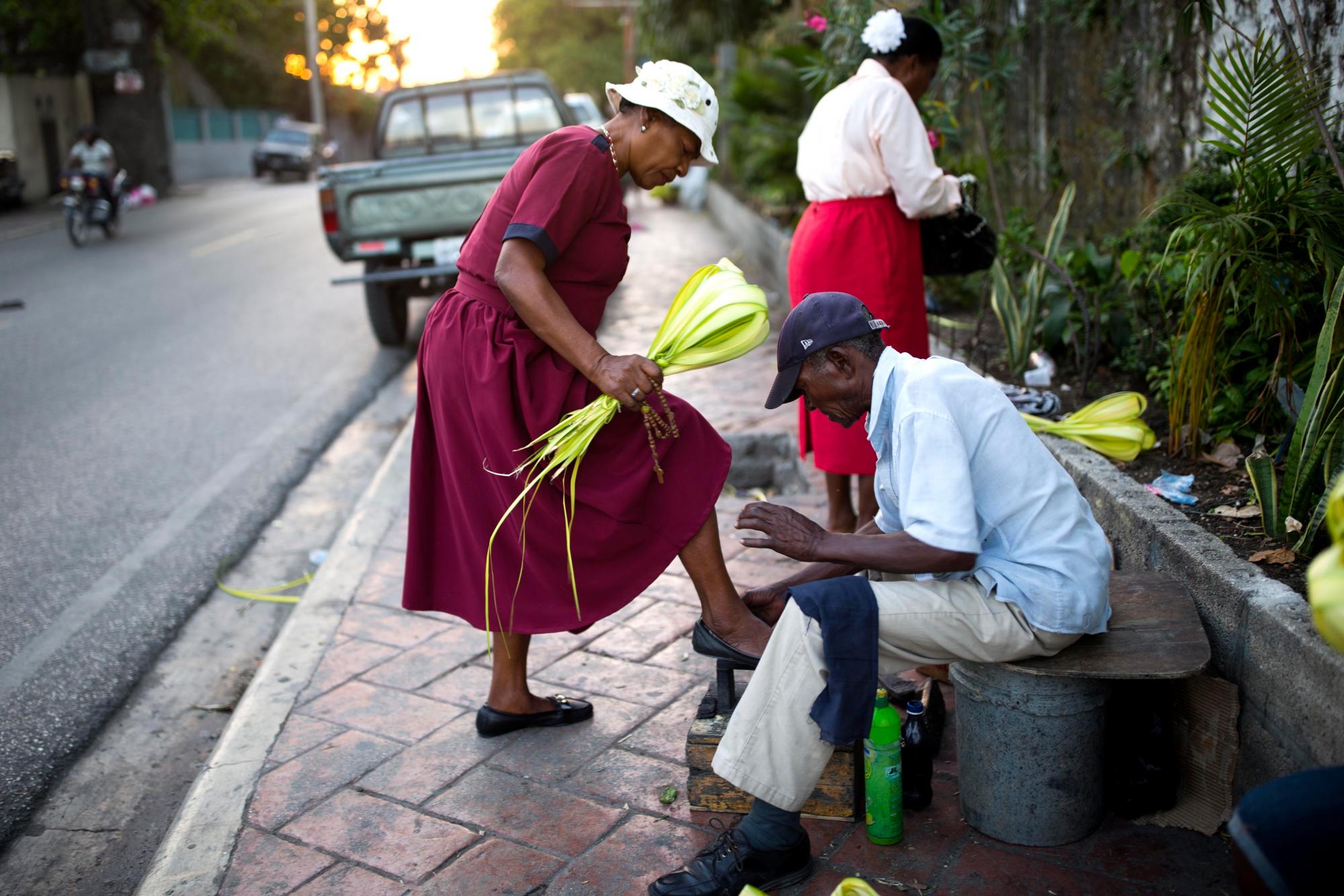 Una mujer brilla sus zapatos antes de asistir A la Misa del Domingo de Ramos en Petion-Ville, Haití. El Domingo de Ramos marca la entrada de Jesucristo en Jerusalén, cuando sus seguidores pusieron ramas de palma en su camino, antes de su crucifixión.