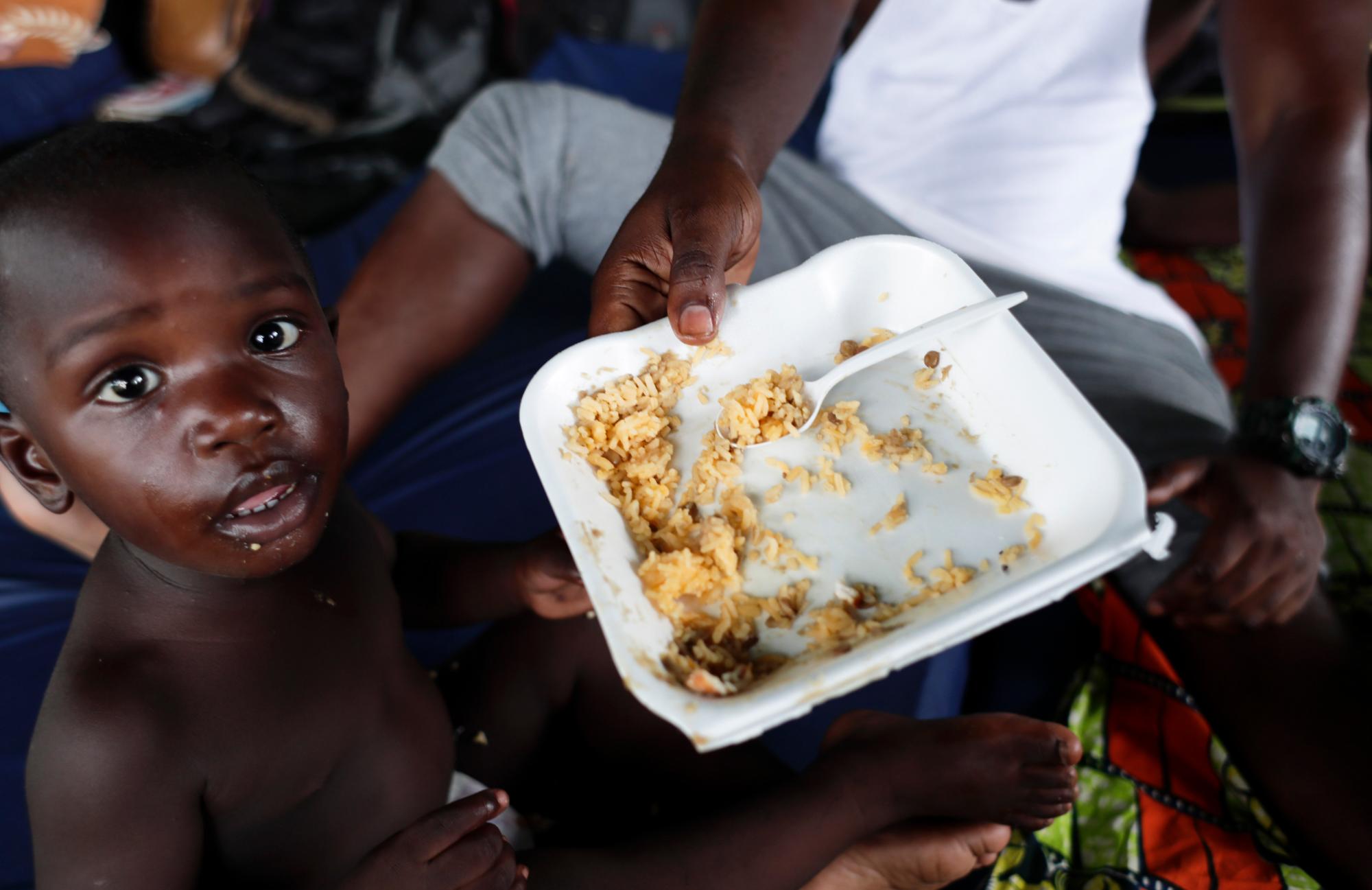 Un hombre da de comer a su hijo en un grandero utlizado como refugio en Peñitas, en la provincia de Darién, Panamá.
