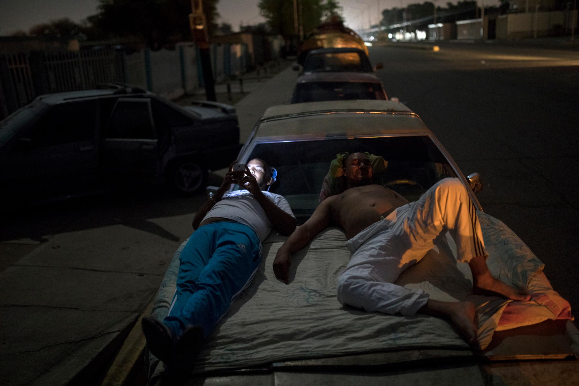 Dos hombres venezolanos esperan montados sobre un vehículo en una cola para conseguir gasolina en Cabimas, Venezuela, el 16 de mayo del 2019.  