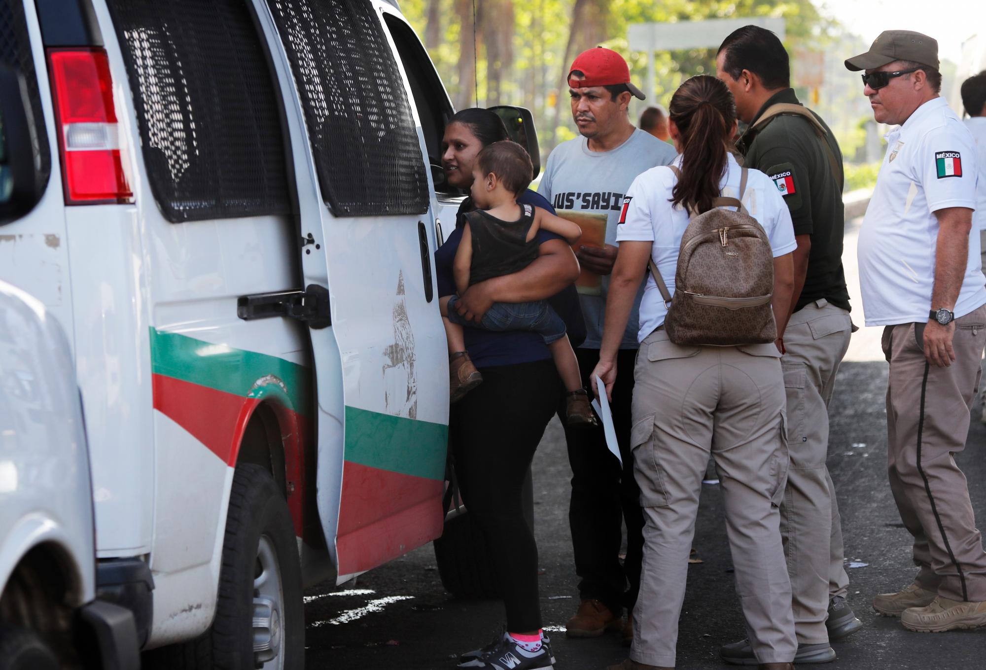 Una mujer migrante centroamericana lleva su hijo a la furgoneta mientras los funcionarios de inmigración mexicanos los toman bajo custodia en Tapachula, México, el lunes 27 de mayo de 2019.