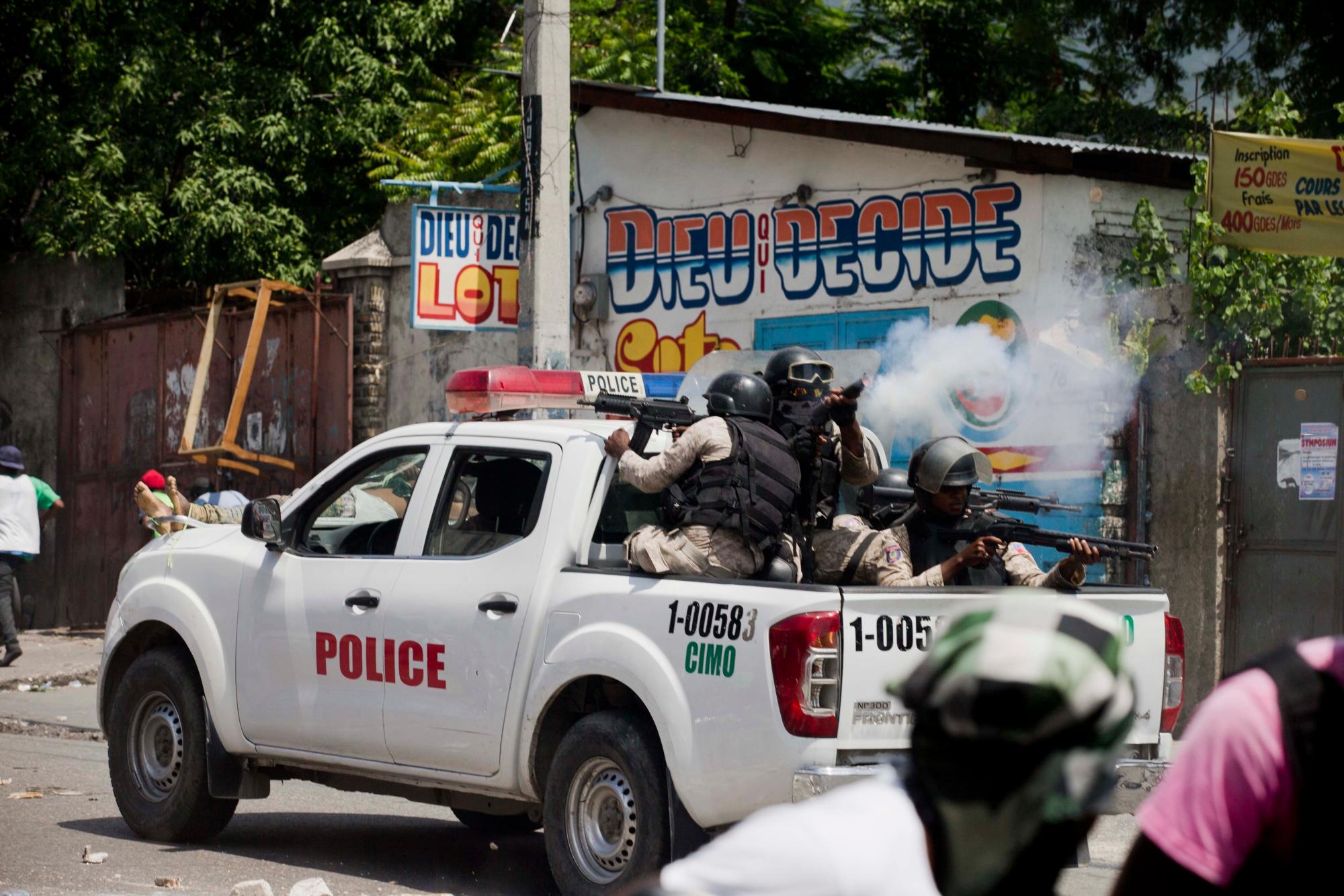 La policía nacional dispara gas lacrimógeno a los manifestantes contra el gobierno de un vehículo en movimiento en Puerto Príncipe, Haití, el domingo 9 de junio de 2019. 