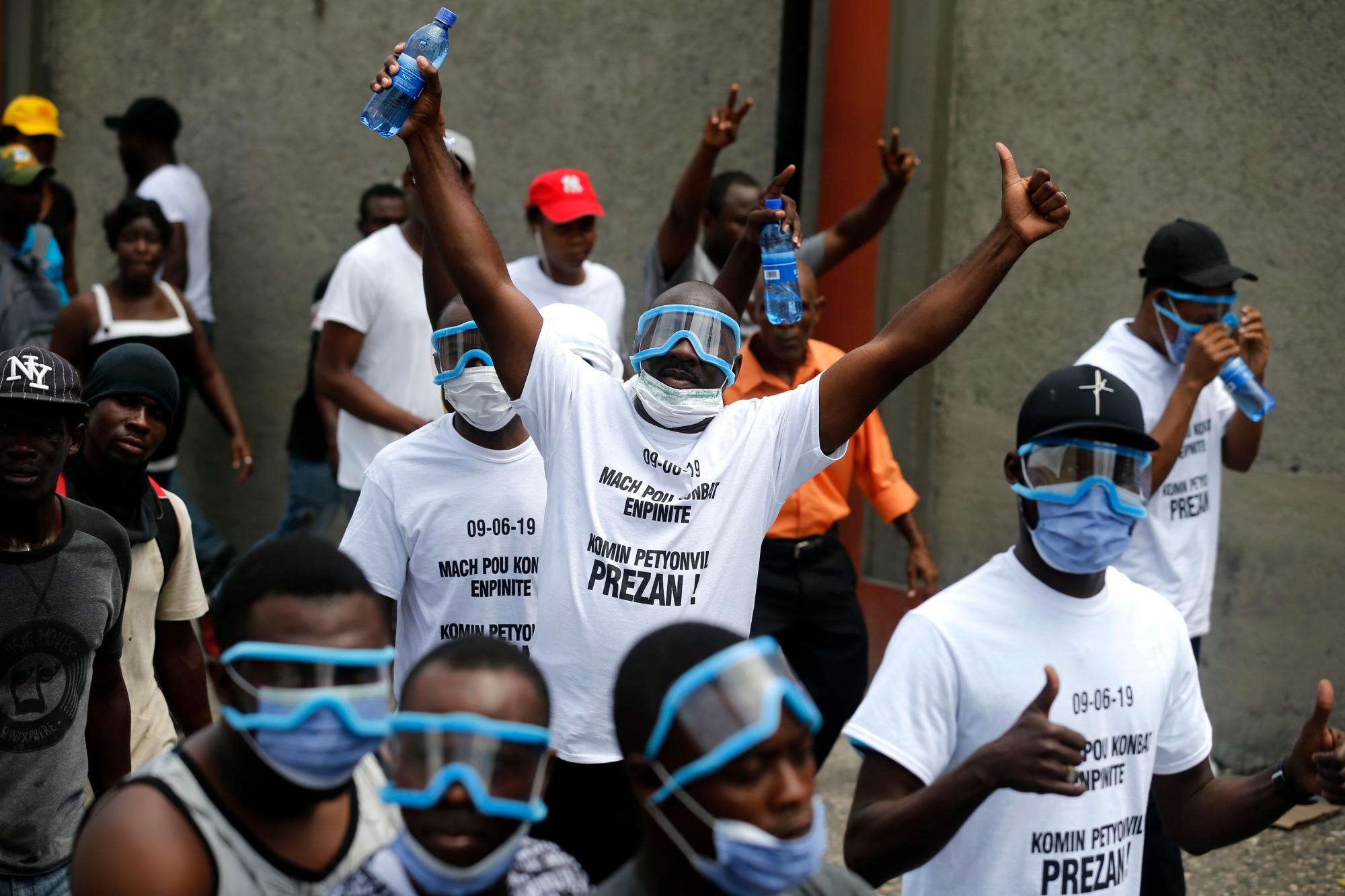 Los manifestantes gesto a la cámara durante una protesta exigiendo la renuncia del Presidente Jovenel Moise en Puerto Príncipe, Haití, el domingo 9 de junio de 2019. Los manifestantes exigen una mayor investigación sobre el destino de los fondos que resultaron de los envíos de petróleo subvencionados procedentes de Venezuela.