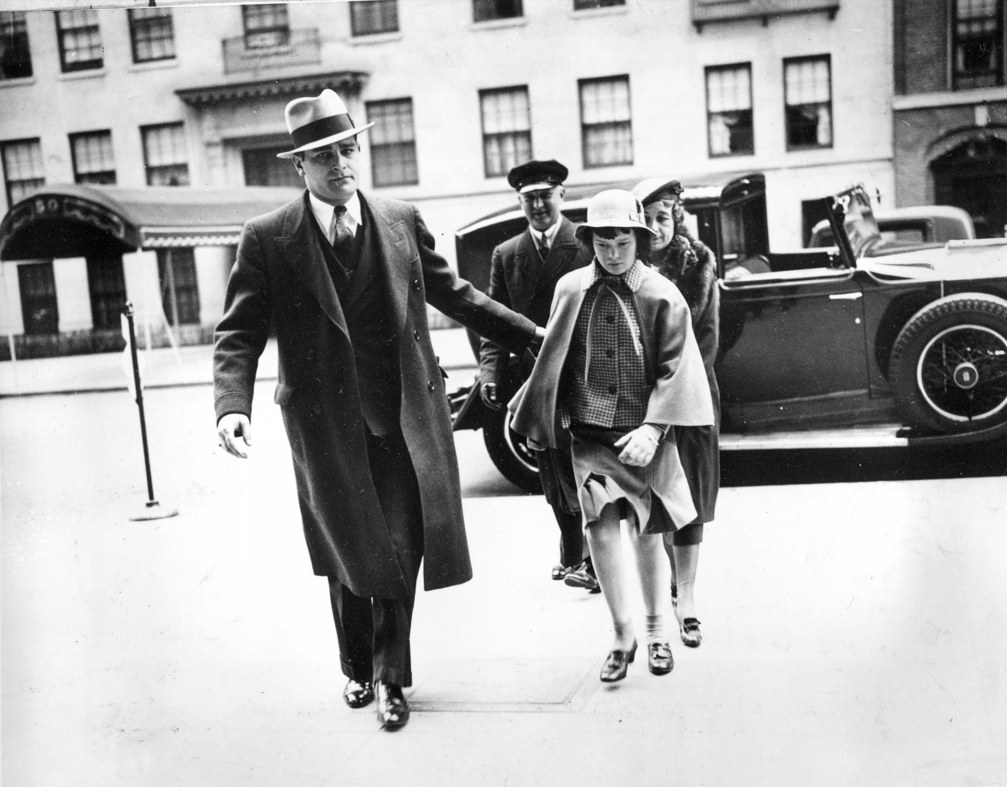 En esta foto del 22 de abril de 1935, Gloria Vanderbilt, acompañada por un guardaespaldas, una enfermera y un chofer, llega a la casa de su madre, Gloria Morgan Vanderbilt, en Nueva York.