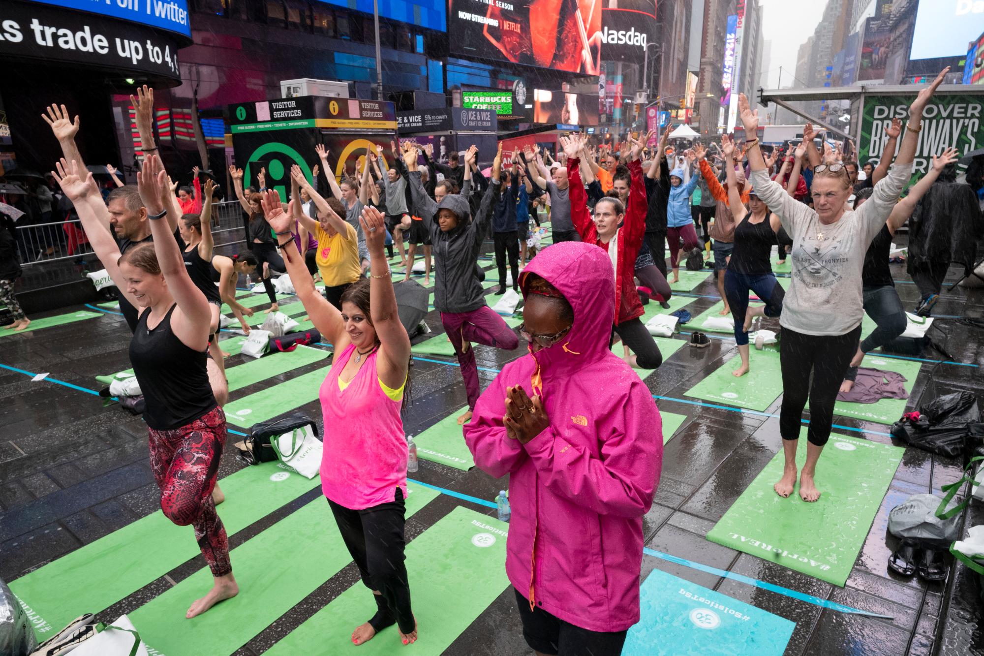 Participantes en el evento de yoga Mind Over Madness para celebrar el solsticio de verano durante una tormenta en el Times Square de Nueva York, el viernes 21 de junio de 2019. 