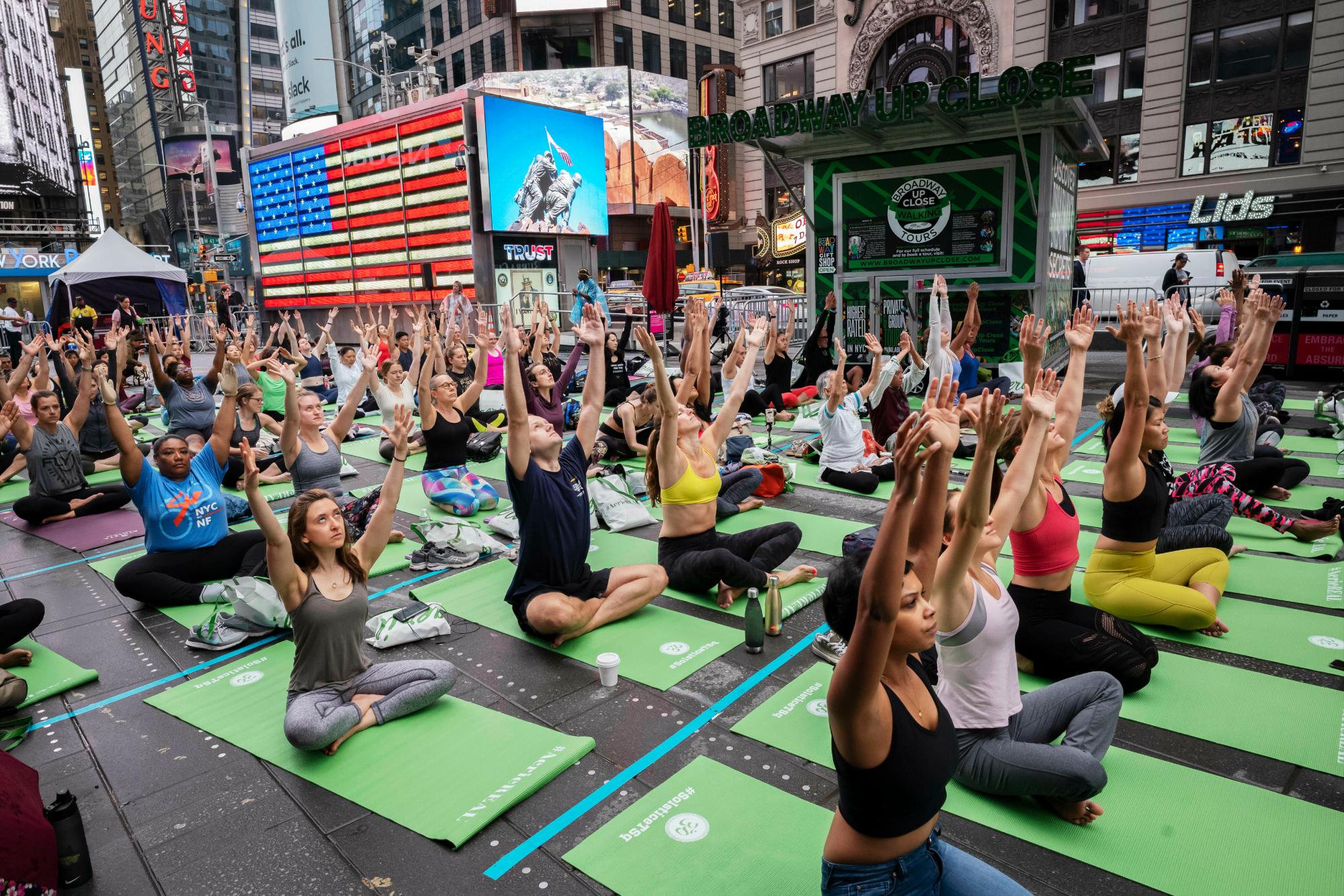 Participantes en el evento de yoga Mind Over Madness para celebrar el solsticio de verano durante una tormenta en el Times Square de Nueva York, el viernes 21 de junio de 2019. 