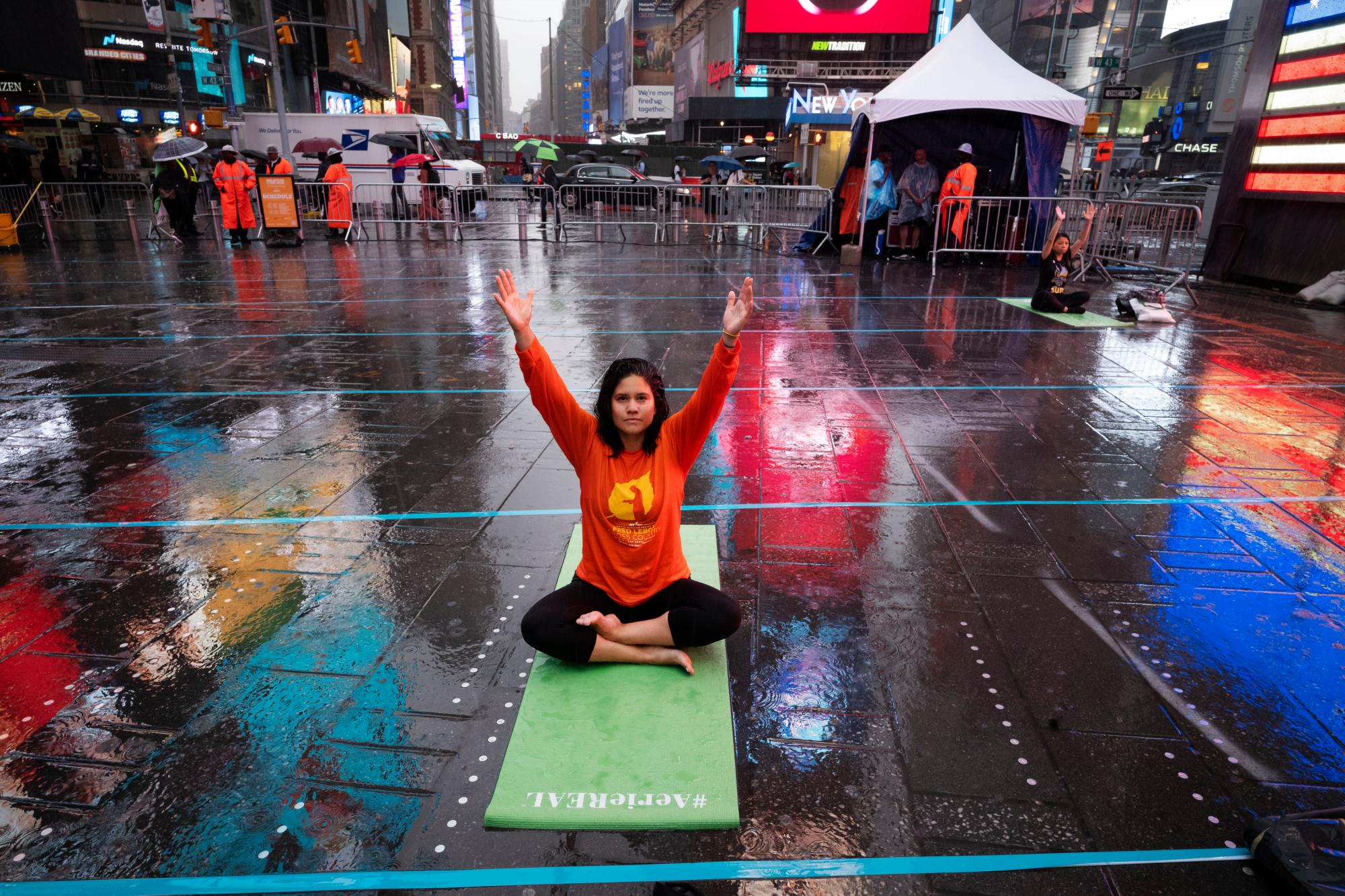 Brenda Barsallo, participa en el evento de yoga Mind Over Madness para celebrar el solsticio de verano durante una tormenta en el Times Square de Nueva York, el viernes 21 de junio de 2019. 