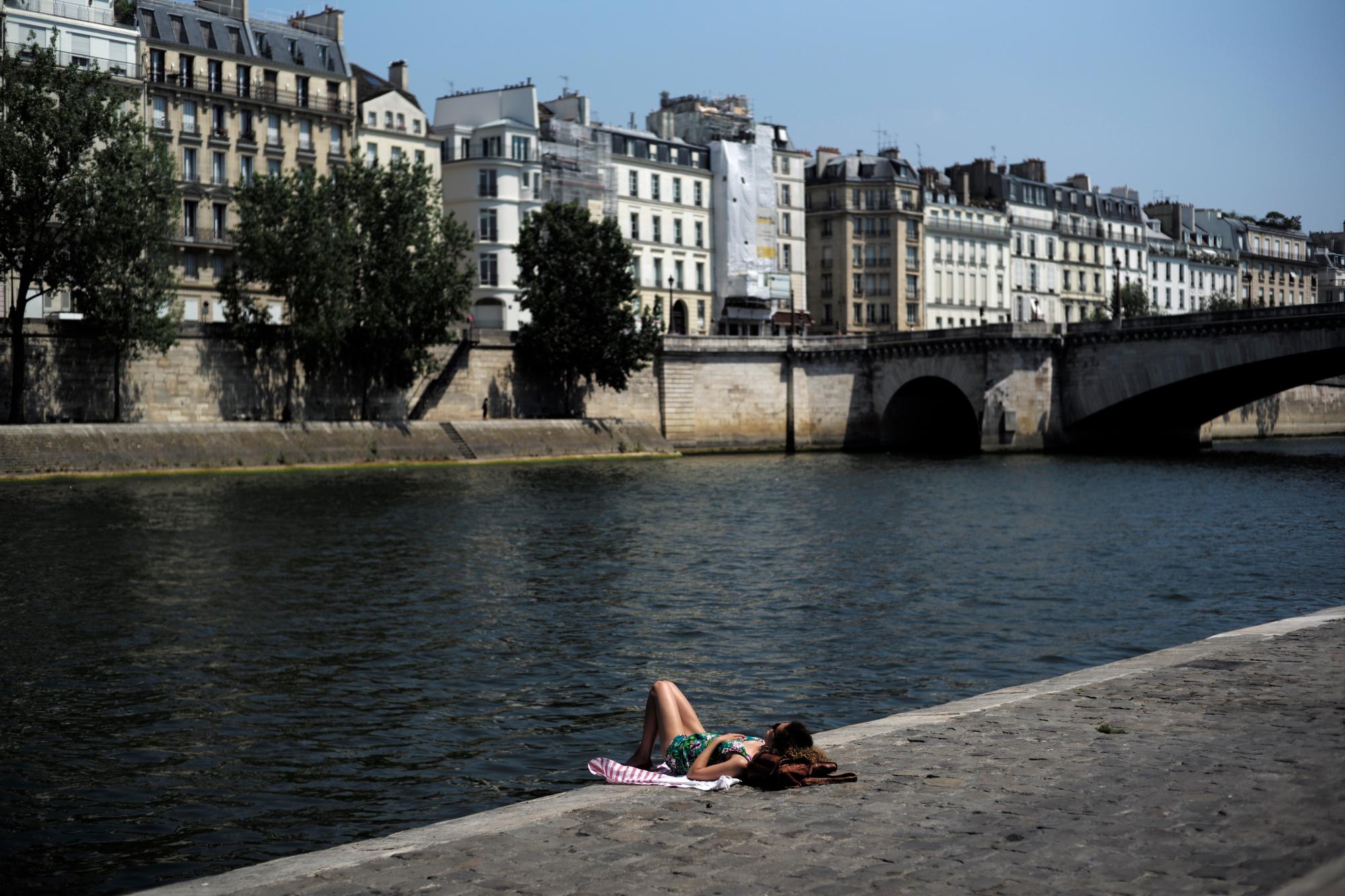 Una mujer toma el sol a lo largo del río Sena, el miércoles 26 de junio de 2019 en París. Se espera que las altas temperaturas suban a 39 grados centígrados (102 grados Fahrenheit) en el área de París a fines de esta semana y que calienten gran parte del país, desde los Pirineos en el suroeste hasta la frontera alemana en el noreste. 