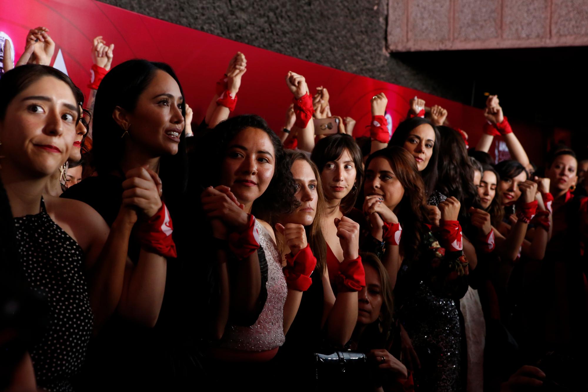 En esta imagen, tomada el 24 de junio de 2019, mujeres del sector cinematográfico mexicano levantan sus puños, donde llevan un pañuelo rojo, en la presentación de la iniciativa #YaEsHora, en la alfombra roja de la 61ra edición de los Premios Ariel de la Academia Mexicana de Artes y Ciencias Cinematográficas, en la Cineteca Nacional de la Ciudad de México. Reclaman igualdad salarial y tolerancia cero hacia el acoso sexual.