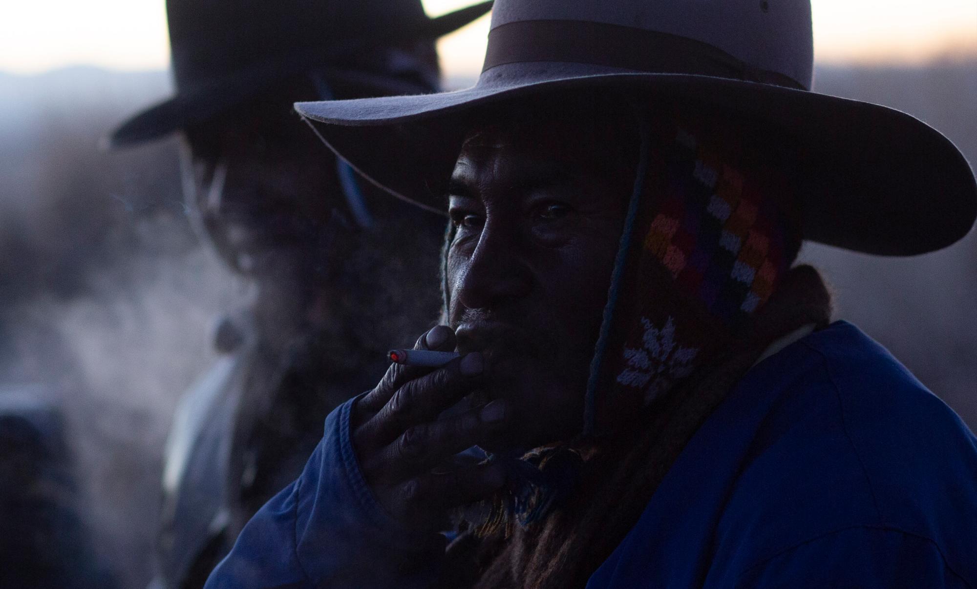 En esta imagen, tomada el 21 de junio de 2019, un aymara fuma un cigarrillo durante un ritual de Año Nuevo en las ruinas de Lukurmata, en Bolivia. Las comunidades aymaras celebran el año 5.527 del calendario andino. 