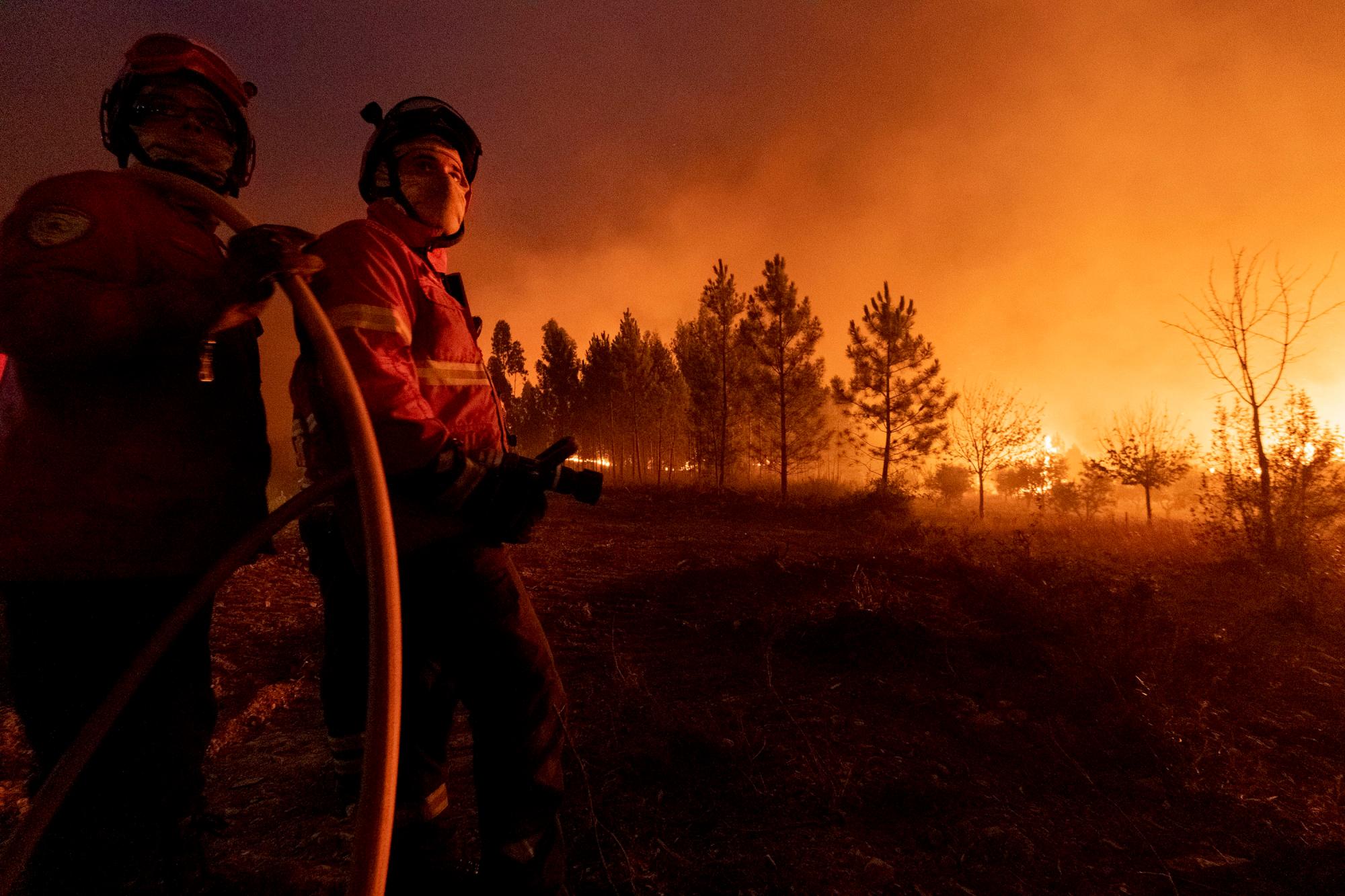 Miembros de los servicios de emergencia intentan apagar un incendio forestal cerca de la aldea de Cardigos, en el centro de Portugal, el domingo 21 de julio de 2019. Unos 1.800 bomberos luchaban por contener los incendios en el centro de Portugal que ya han herido a personas, incluidos varios bomberos, dijeron las autoridades el domingo. 