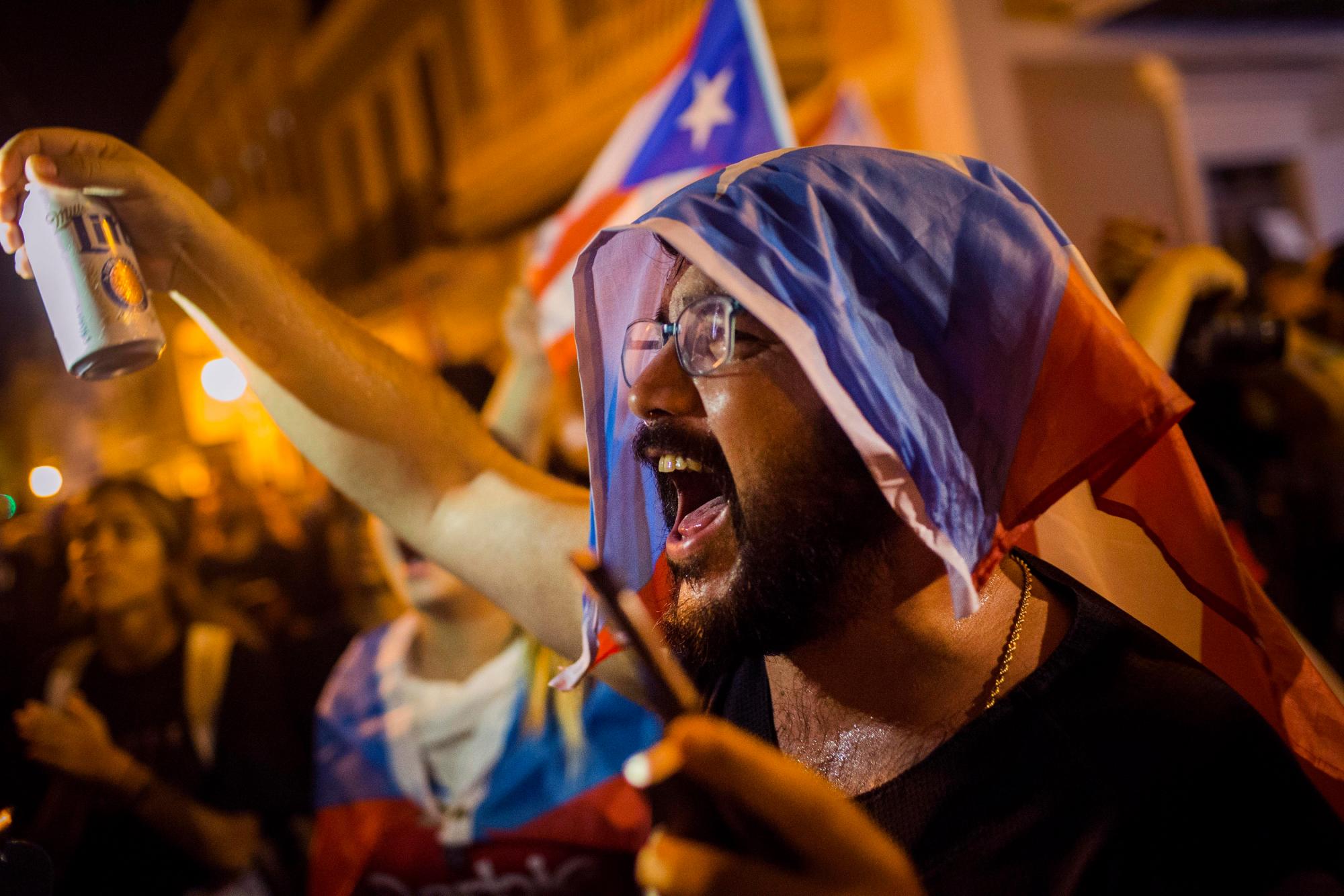 Un manifestante con una bandera puertorriqueña sobre la cabeza protesta en contra del gobernador de la isla, Ricardo Rosselló, el martes 23 de julio del 2019 en San Juan, Puerto Rico. 