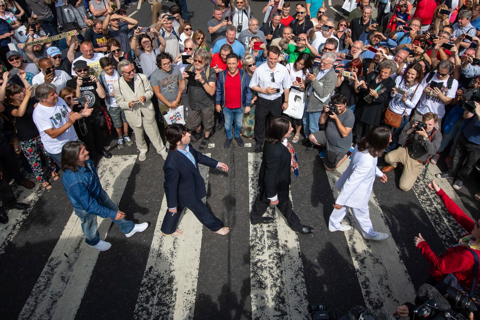 Miles de fanáticos se reúnen para cruzar el paso de cebra de Abbey Road, en el 50 aniversario de los músicos pop británicos The Beatles que lo hicieron para la portada de su álbum ‘Abbey Road’ en St Johns Wood en Londres, el jueves 8 de agosto de 2019. Su objetivo era cruzar 50 años al minuto desde que los ‘Fab Four’ fueron fotografiados para el álbum.