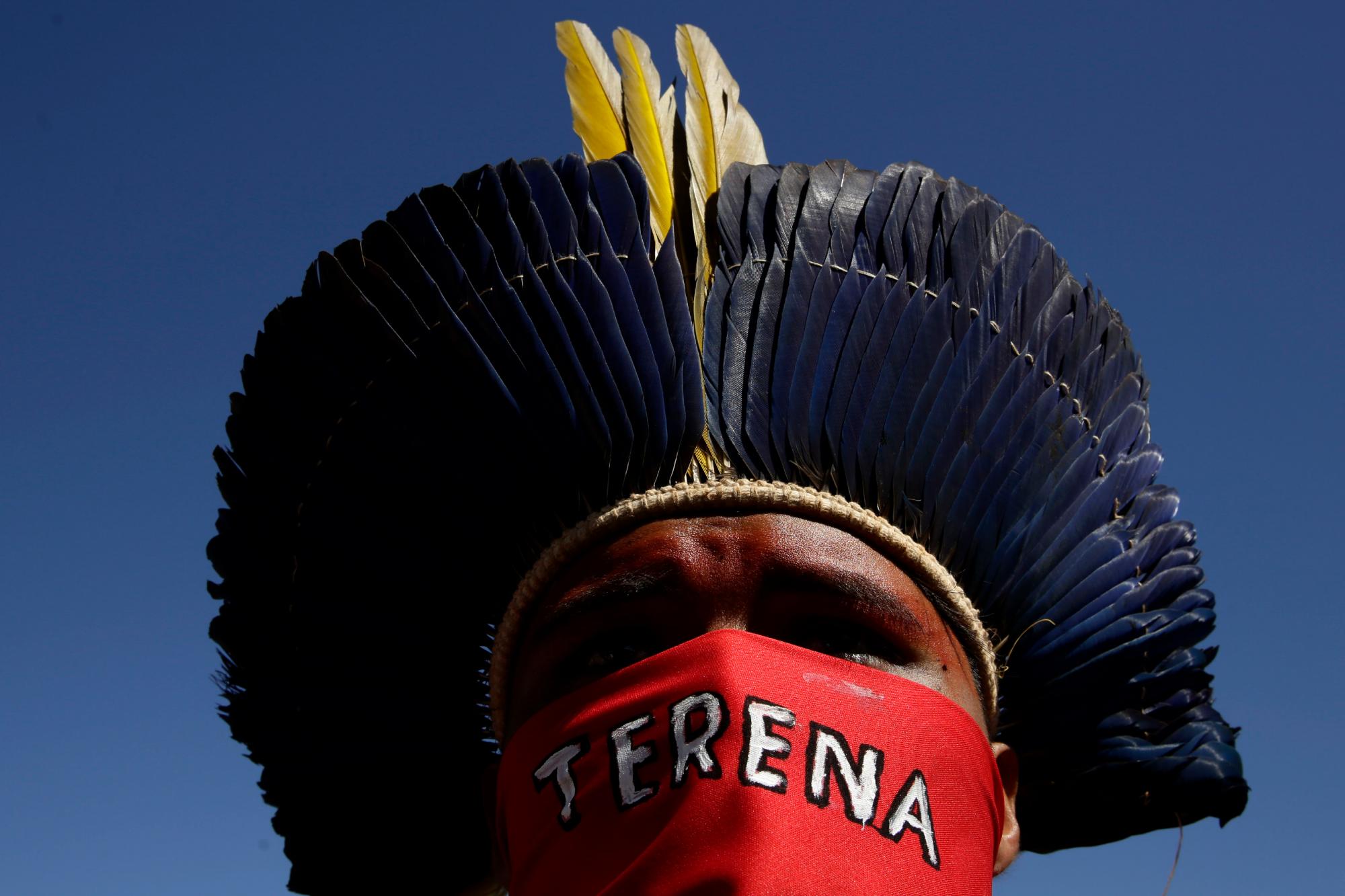 Un joven guerrero indígena se cubre la cara con un paño que tiene el nombre de su pueblo, Terena, escrito durante una Marcha de Mujeres Indígenas, en Brasilia, Brasil, el martes 13 de agosto de 2019. Cientos de mujeres indígenas llegaron a la capital para protestar por las políticas del presidente Jair Bolsonaro. 