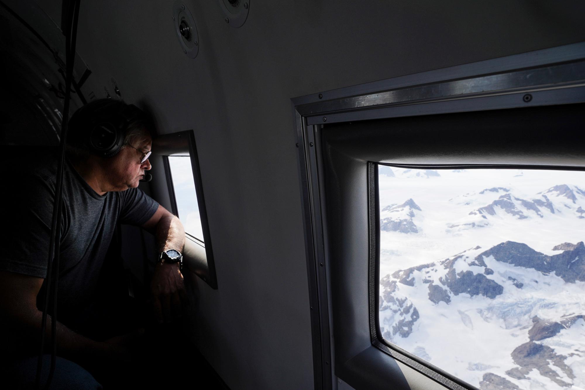 En esta foto tomada el miércoles 14 de agosto de 2019, el gerente del proyecto de la NASA, Ian McCubbin, mira por la ventana de un avión mientras vuelan en una misión para rastrear el hielo derretido en el este de Groenlandia. Groenlandia se ha derretido más rápido en la última década y este verano, ha visto dos de los mayores derretimientos registrados desde 2012. 