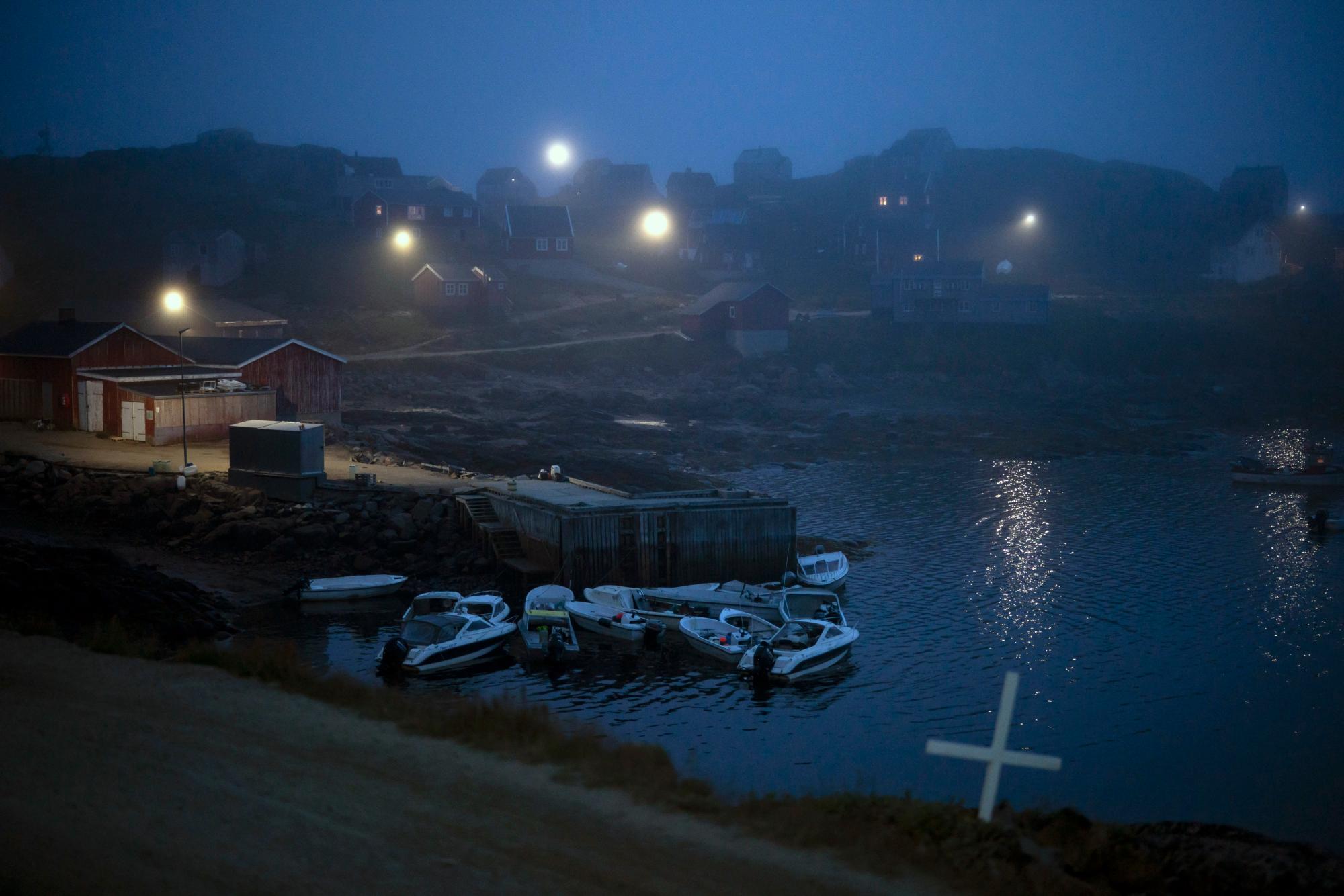 Una cruz se encuentra al costado del camino mientras la niebla cubre las casas en Kulusuk, Groenlandia, el jueves 15 de agosto de 2019 temprano. Groenlandia se ha derretido más rápido en la última década y este verano, ha visto dos de los derretimientos más grandes registrados desde 2012. 