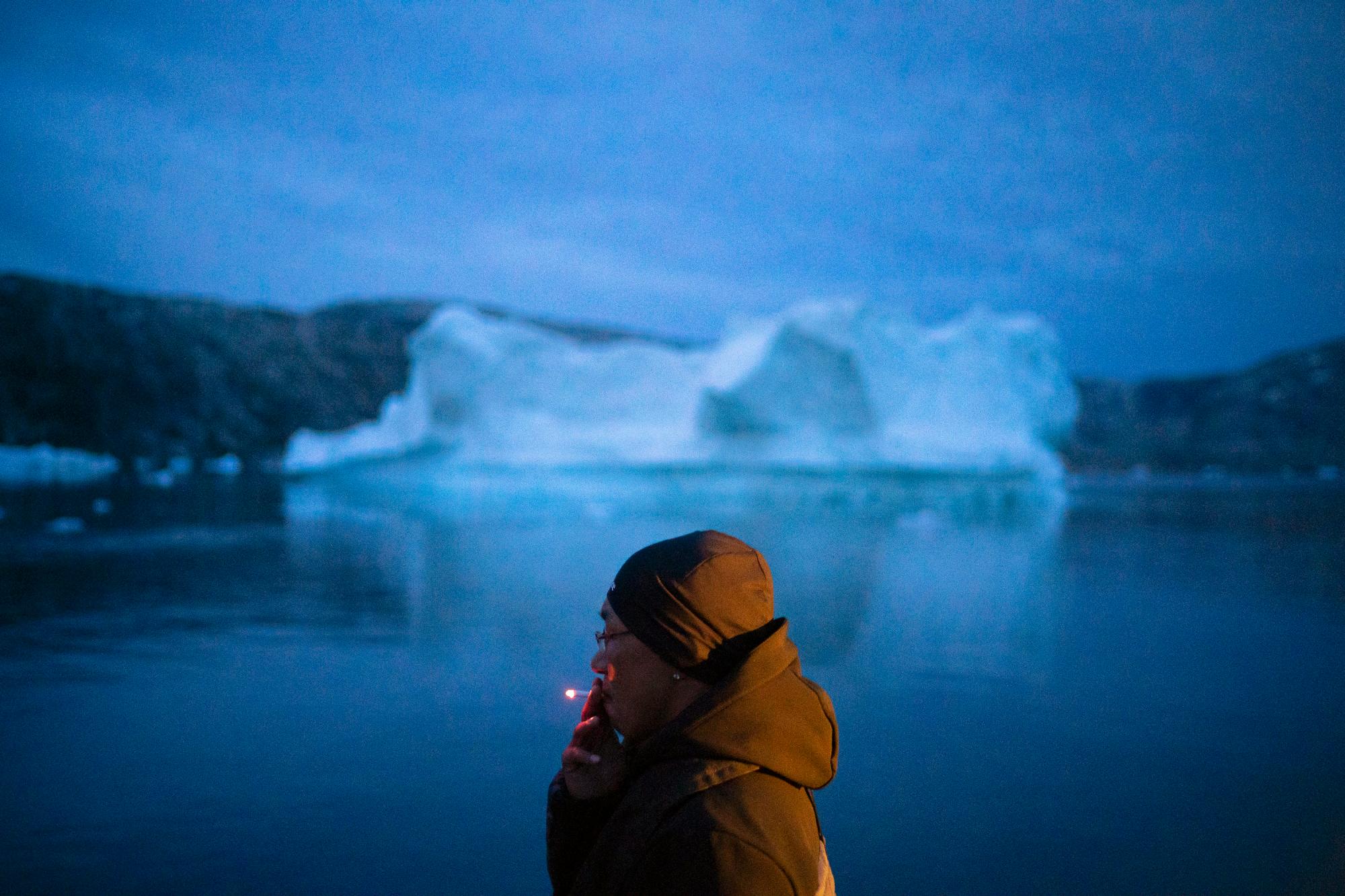Un hombre local fuma un cigarrillo mientras viaja en un bote junto a los icebergs en el este de Groenlandia, a última hora del viernes 15 de agosto de 2019. Groenlandia se ha derretido más rápido en la última década y este verano, ha visto dos de los mayores derretimientos registrados desde 2012. 