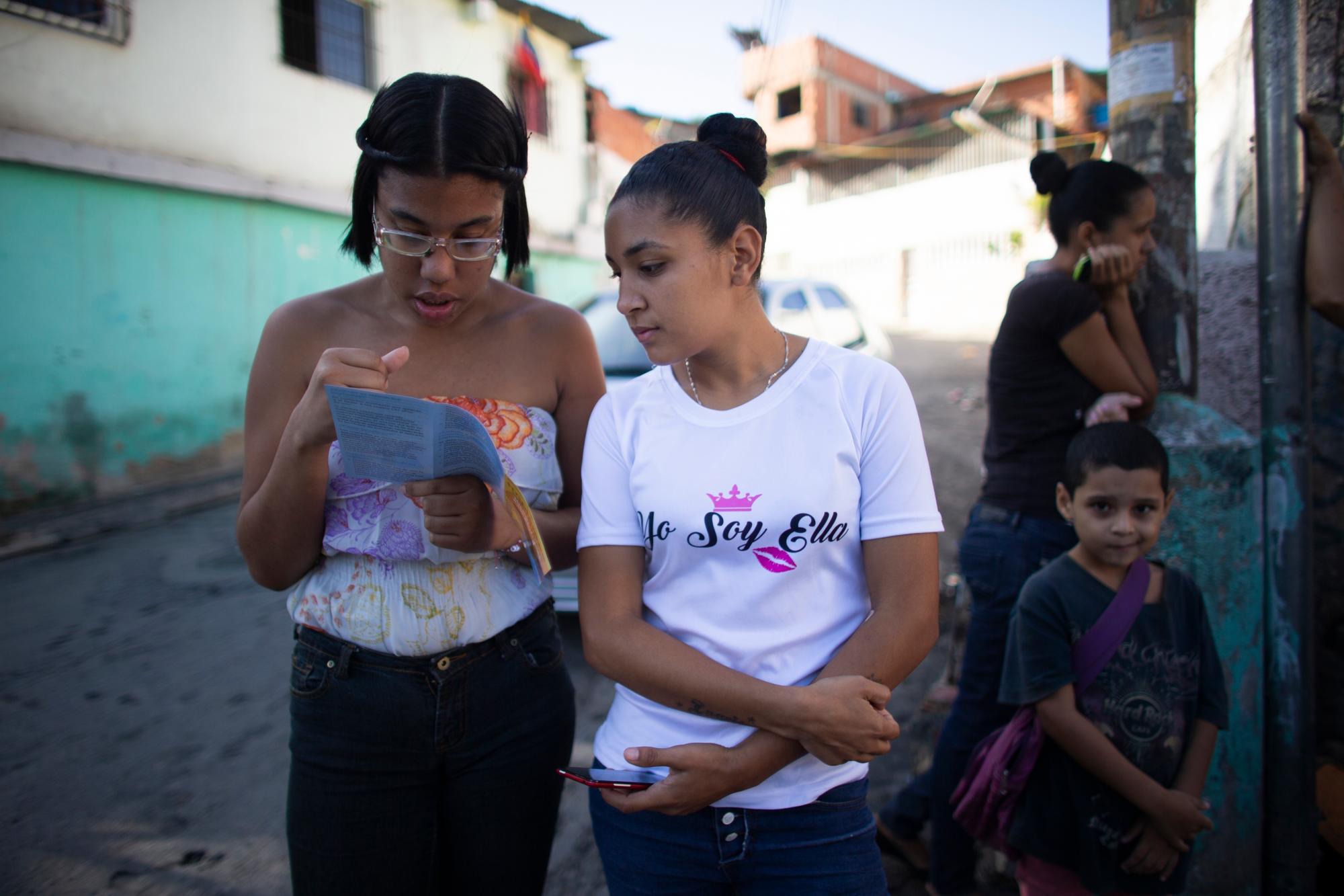 En esta foto tomada el 25 de julio de 2019, las mujeres jóvenes leen un folleto sobre implantes hormonales fuera de una clínica donde se administra un número muy limitado en el barrio de Caucaguita, en las afueras de Caracas, Venezuela. “Las mujeres quedan embarazadas y no tienen opciones”, dijo Luisa Kislinger, una activista de los derechos de las mujeres. “Son forzados a la maternidad”. 
