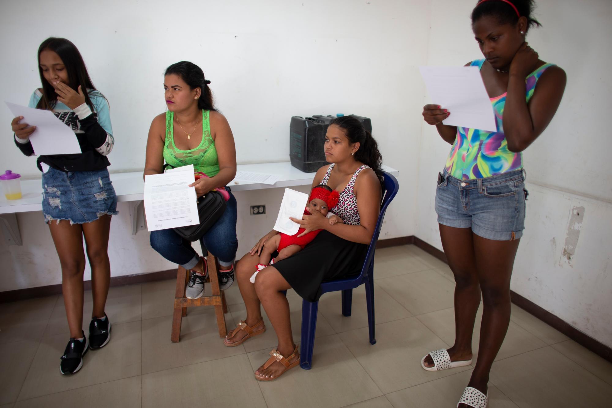 En esta foto tomada el 25 de julio de 2019, Nicol Ramírez, de 15 años, se sienta con su bebé y otras mujeres con formularios para firmar que autorizan la administración de implantes hormonales para prevenir embarazos, de los cuales hay un número muy limitado, en el barrio de Caucaguita. en las afueras de Caracas, Venezuela. Con condones y píldoras anticonceptivas imposibles de encontrar o demasiado caras, Ramírez descubrió que estaba embarazada a los 14 años con su novio, quien respondió fríamente a su embarazo y no ha tenido noticias suyas desde entonces. “La situación en este país no es la de tener hijos”, dijo Ramírez. “Todavía soy una niña”. 