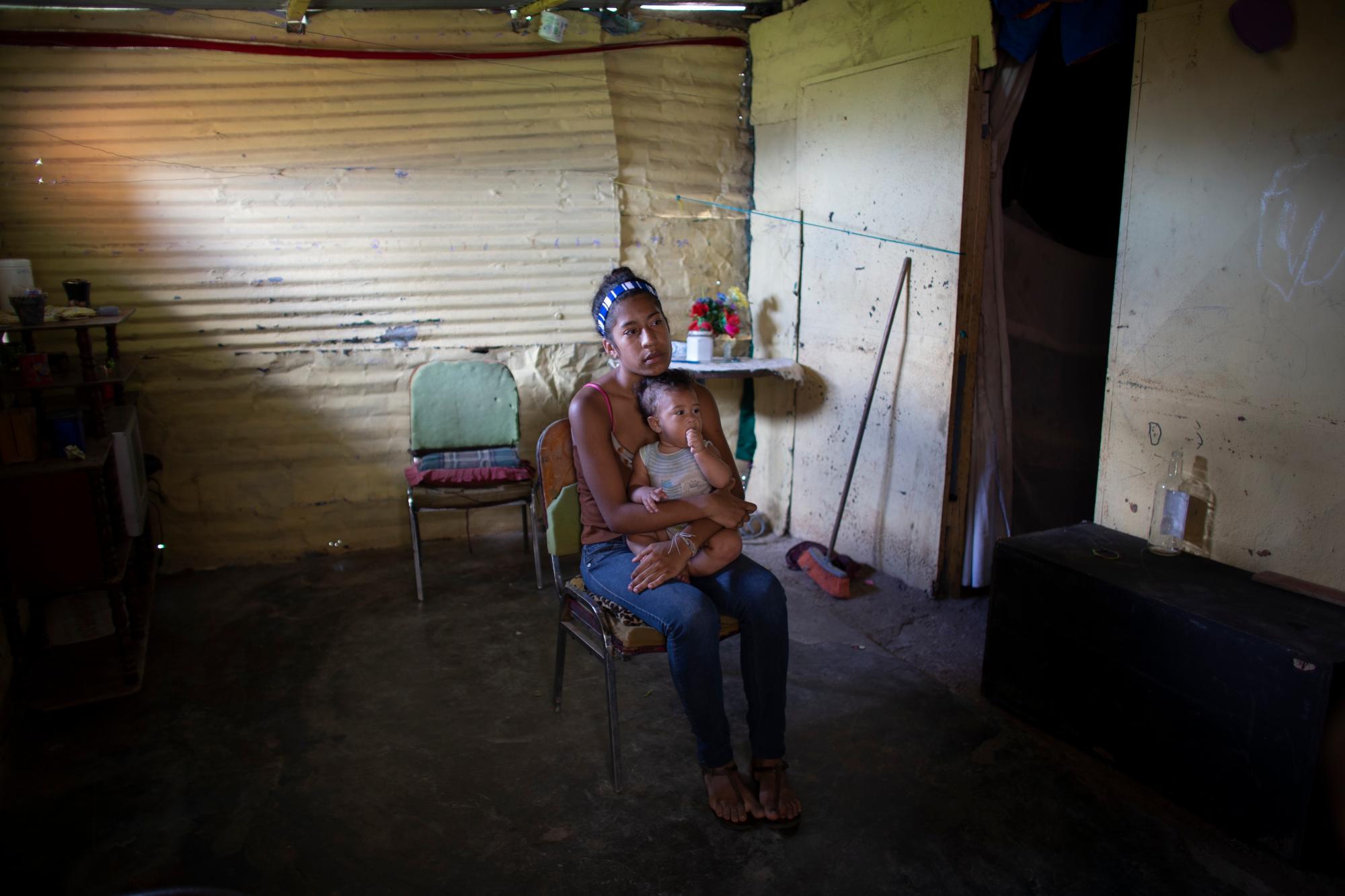 En esta foto tomada el 25 de julio de 2019, Karelys Herrera, de 15 años, sostiene a su bebé dentro de su casa durante una entrevista en el barrio de Caucaguita, en las afueras de Caracas, Venezuela. Herrera dijo que contemplaba el suicidio después de enterarse de que estaba embarazada a los 14 años. 