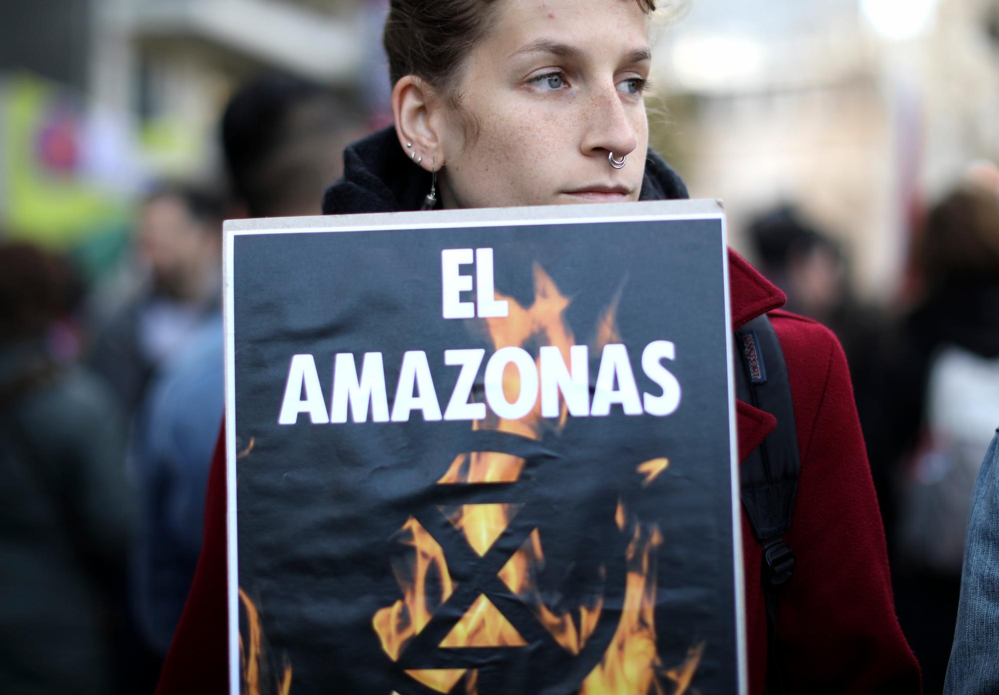 Una mujer sostiene un cartel que dice en español “El Amazonas está en llamas” durante una protesta frente a la Embajada de Brasil para pedirle al presidente de Brasil, Jair Bolsonaro, que actúe para proteger la selva amazónica, en Buenos Aires, Argentina, el viernes 23 de agosto de 2019.