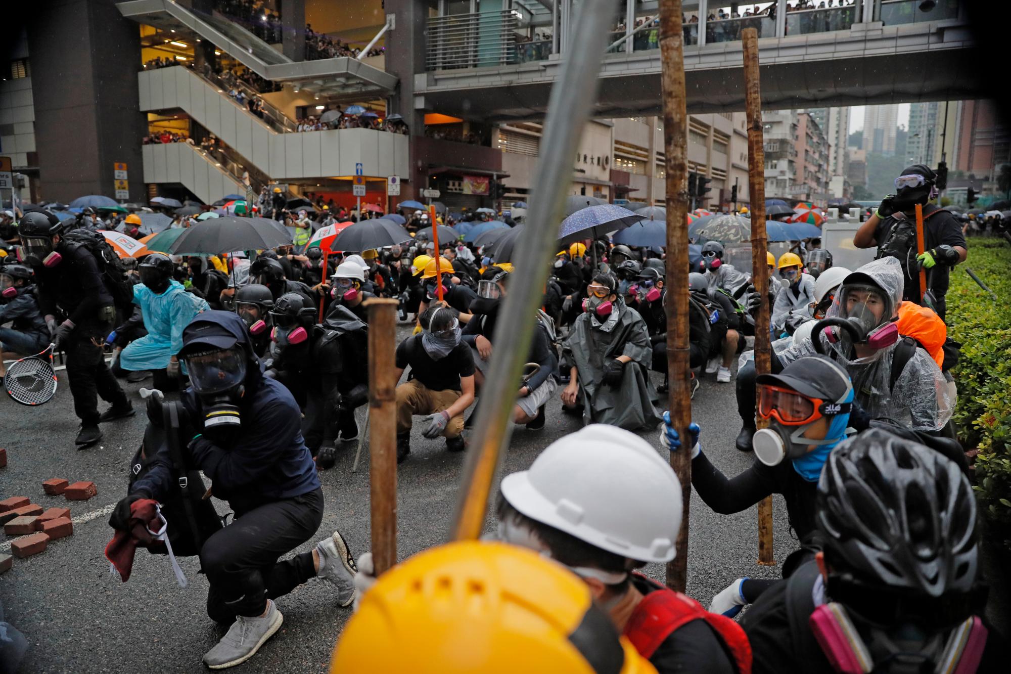 Los manifestantes se agachan detrás de una barricada durante una protesta en Hong Kong, el domingo 25 de agosto de 2019. La policía en Hong Kong usó gases lacrimógenos el domingo para despejar a los manifestantes prodemocráticos que se habían apoderado de una calle y se usaron camiones de cañones de agua por primera vez. 