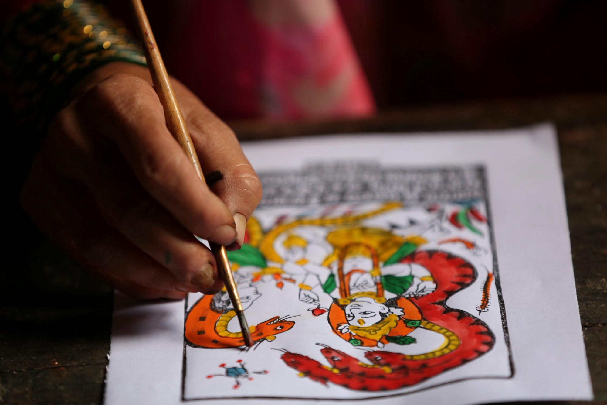 En esta foto del 31 de julio de 2019, Tej Kumari Chitrakar realiza una pintura tradicional para el festivar de Naag Panchami en su casa en Bhaktapur, Nepal. Una pareja de la casta nepalí Chitrakar lucha por mantener vivo el arte tradicional de pintar dioses 