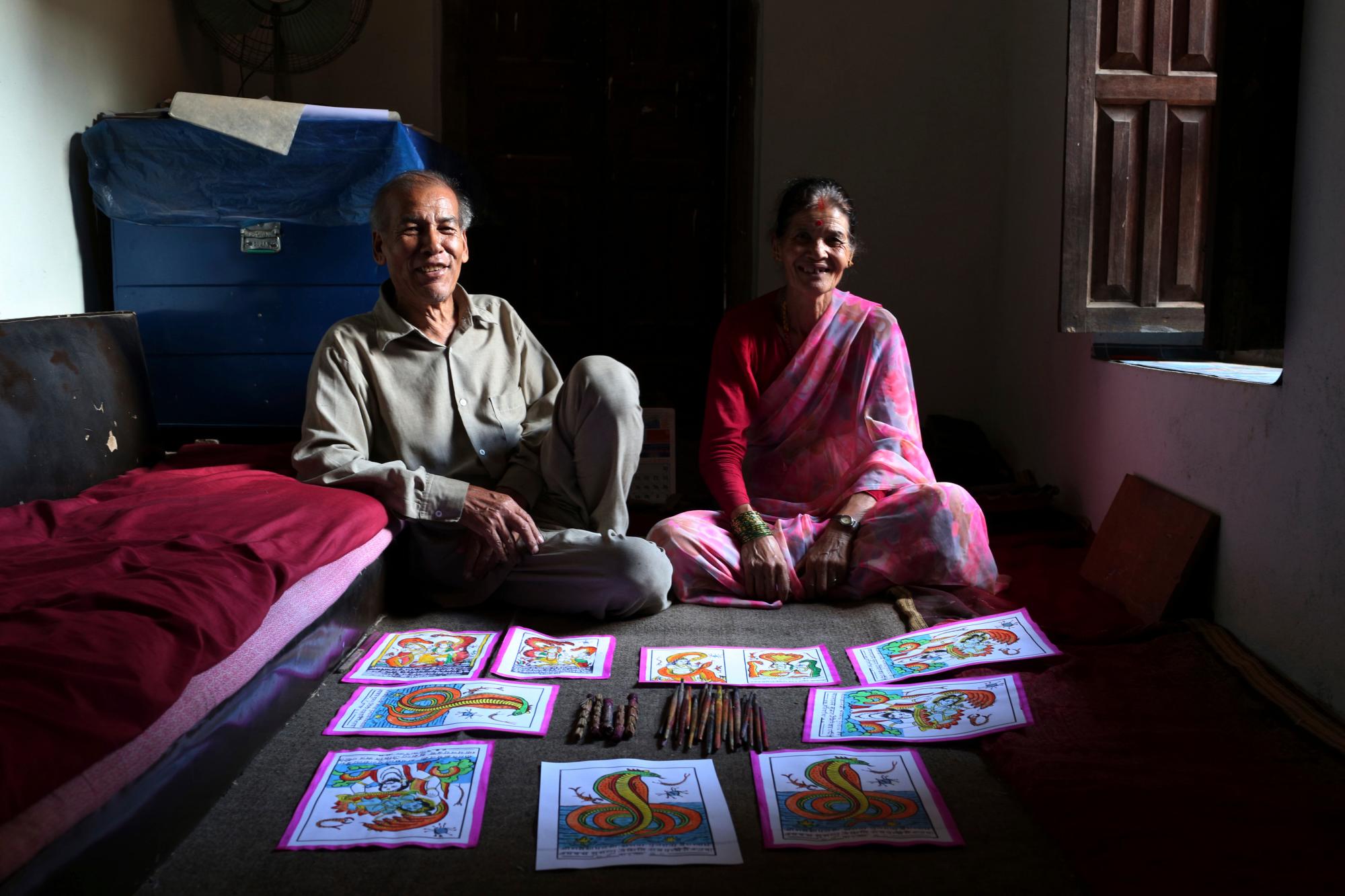 En esta foto del 31 de julio de 2019, la pareja Chitrakar de Tej Kumari y Purna, izquierda, posan en su casa en Bhaktapur, Nepal. La pareja de la casta nepalí Chitrakar lucha por mantener vivo el arte tradicional de pintar dioses. 