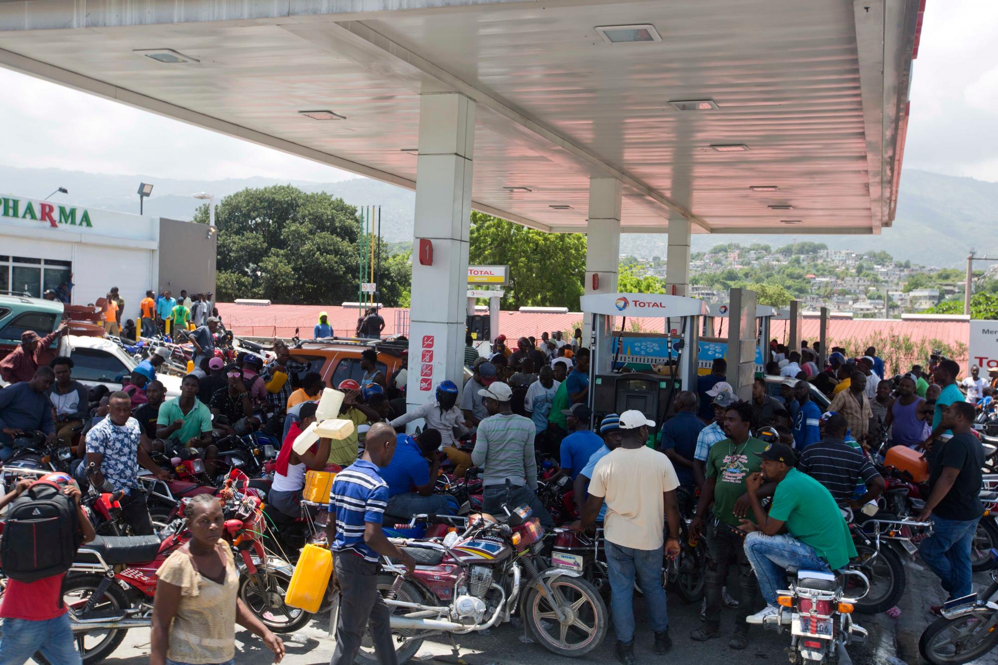 La gente se reúne en una estación de servicio cerrada, esperando que se abra eventualmente, durante una escasez de combustible en Puerto Príncipe, Haití, el lunes 2 de septiembre de 2019. Las estaciones han estado reduciendo sus horas de operación durante las últimas dos semanas, el domingo todas las estaciones estaban cerradas. 