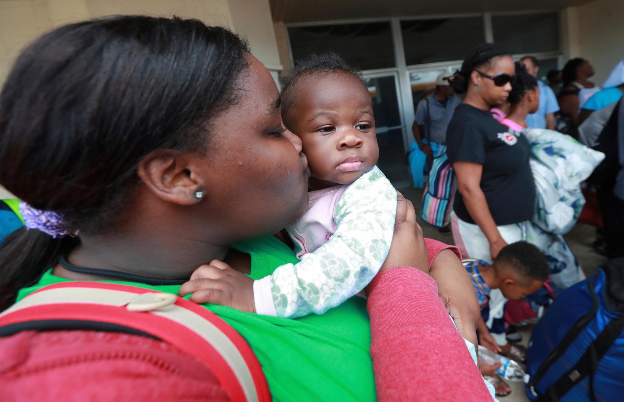 Verida Hemphill le da a su sobrina Laniyah Harsey, de 6 meses, un beso en la mejilla para consolarla mientras ellos y otros residentes abordan los autobuses en Lanier Plaza para abandonar el área bajo evacuación obligatoria antes del huracán Dorian, el lunes 2 de septiembre de 2019. en Brunswick, Georgia 