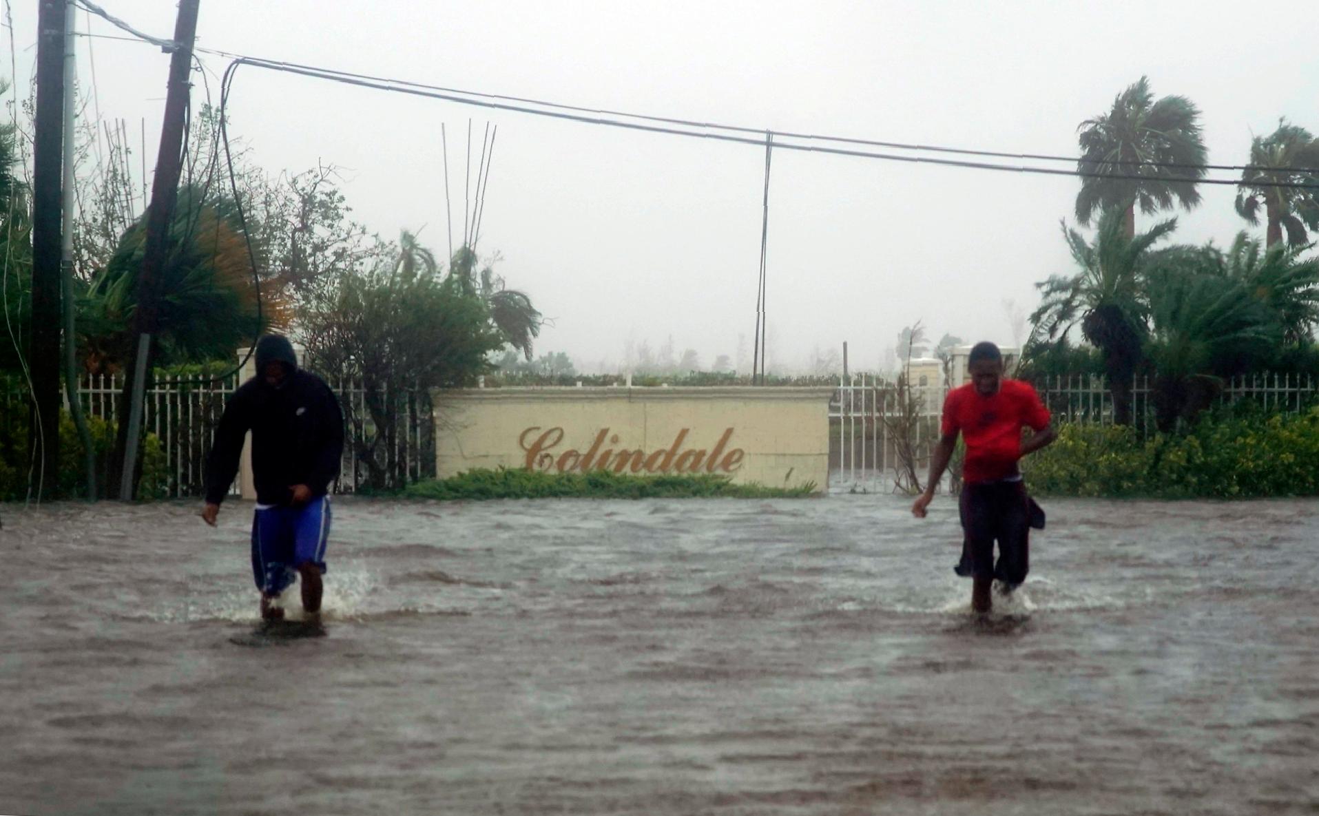 Los residentes deambulan por una calle inundada de agua provocada por el huracán Dorian en Freeport, Bahamas, el martes 3 de septiembre de 2019. Dorian comienza a avanzar lentamente hacia el noroeste después de estar inmóvil sobre las Bahamas, donde sus vientos implacables han causado daños catastróficos e inundaciones. 