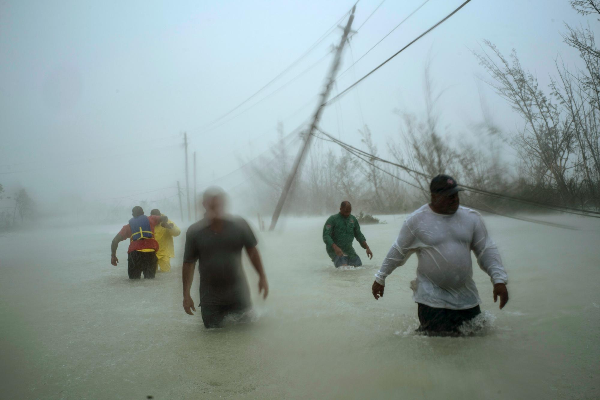 Los voluntarios caminan bajo el viento y la lluvia del huracán Dorian a través de una carretera inundada mientras trabajan para rescatar a las familias cerca del puente Causarina en Freeport, Gran Bahama, Bahamas, el martes 3 de septiembre de 2019. Los fuertes vientos de la tormenta y las aguas marrones fangosas devastaron a miles de hogares.