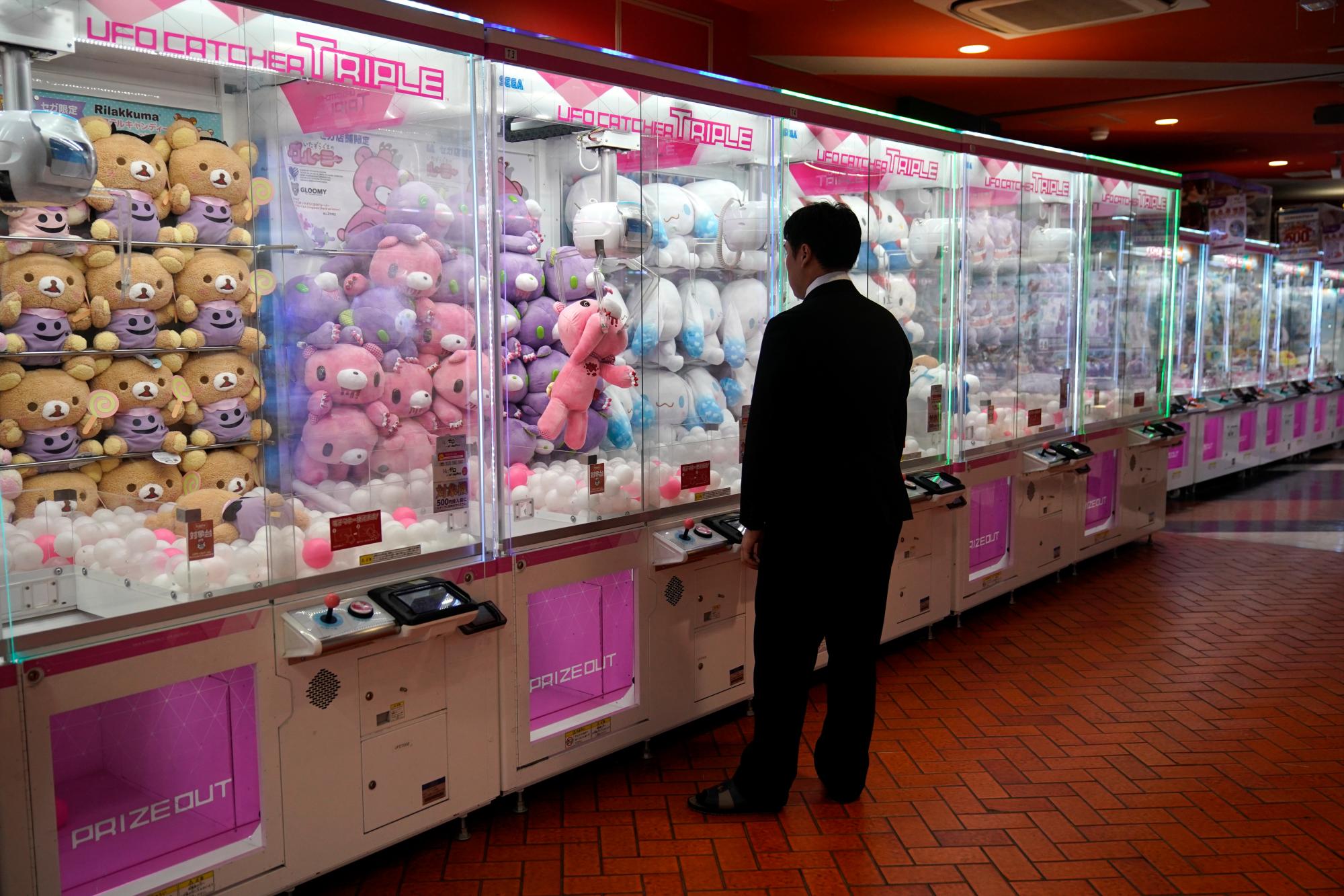 Un hombre vestido con un traje observa cómo una muñeca que agarró con la garra de la máquina se deja caer nuevamente dentro de la caja mientras juega un juego de grúas el miércoles 11 de septiembre de 2019 en el distrito de Akihabara de Tokio. 