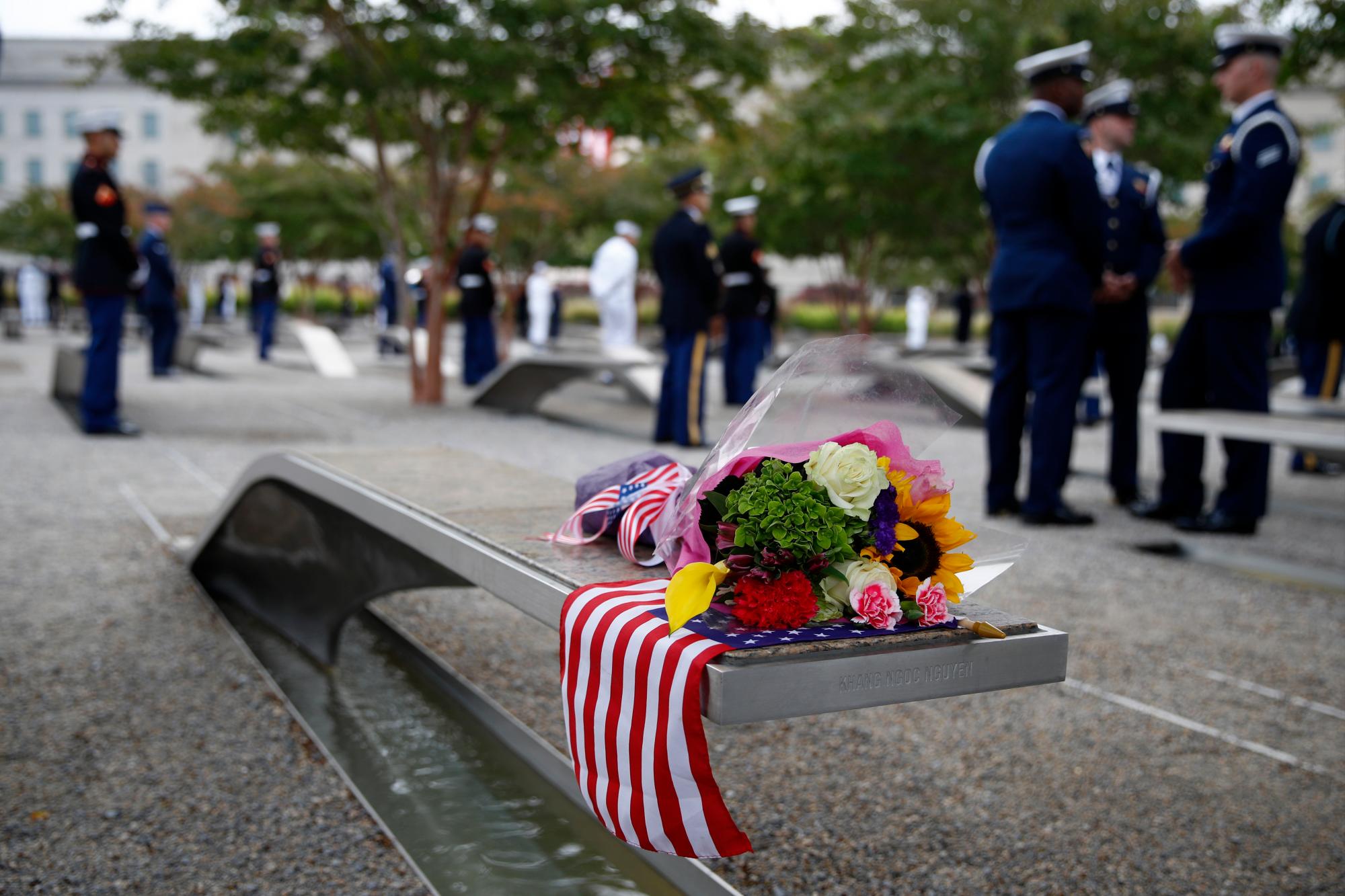 Flores y una bandera estadounidense descansan en un banco con un nombre en memoria de Khang Ngoc Nguyen antes de una ceremonia en celebración del 18 aniversario de los ataques del 11 de septiembre en el Pentágono en Washington, el miércoles 11 de septiembre de 2019. 
