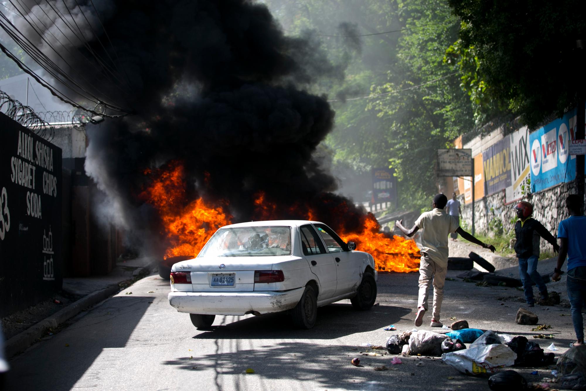 Un automóvil se detiene junto a una barricada incendiada creada por personas que protestaban por la escasez de combustible en Petion-ville, Haití, el domingo 15 de septiembre de 2019. Las estaciones de servicio han estado reduciendo sus horas de funcionamiento en las últimas semanas y la mayoría cerraron esta semana. 