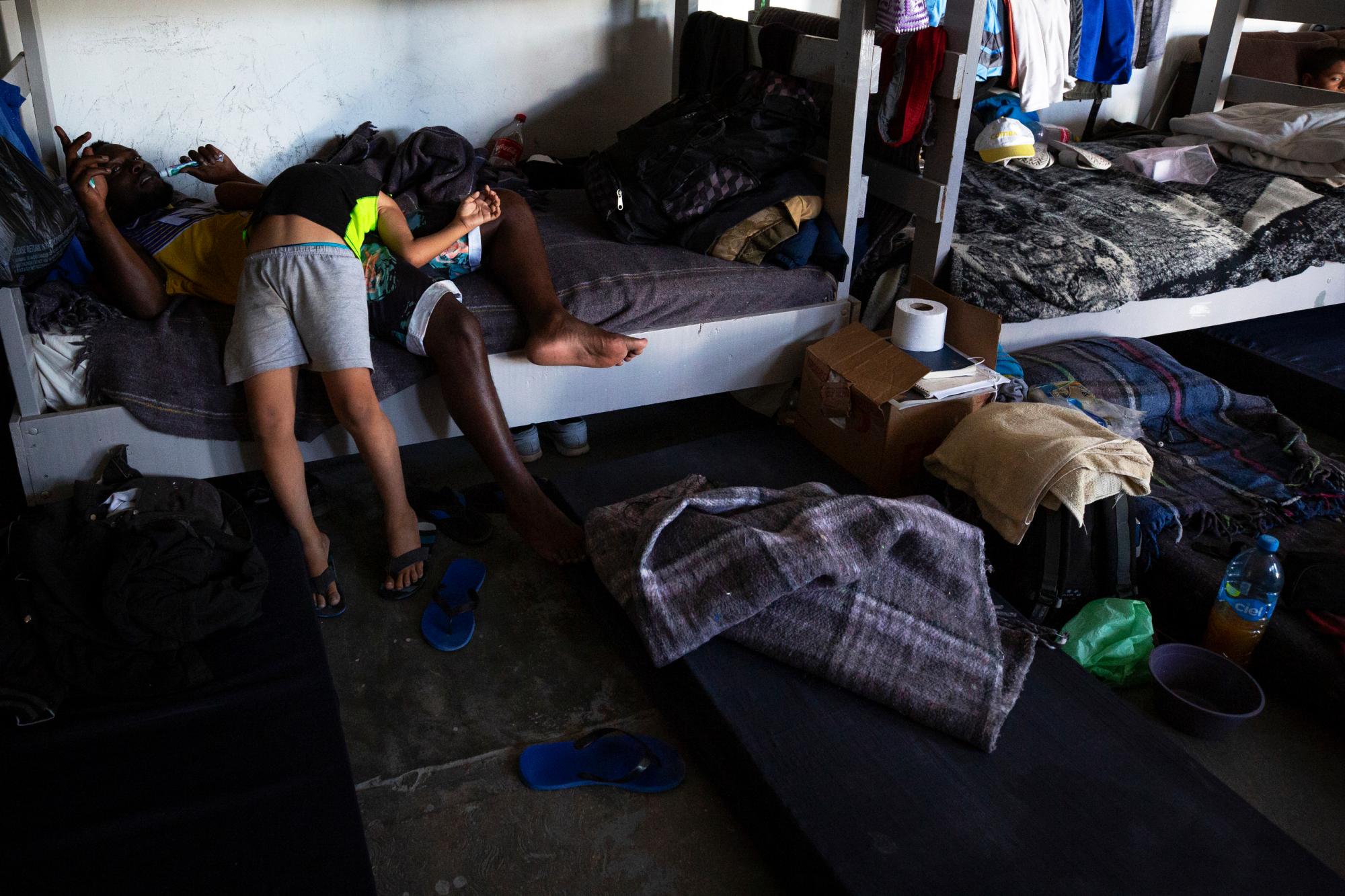 En esta foto del 25 de julio de 2019, un niño de Honduras bromea con un hombre africano en el dormitorio del refugio El Buen Pastor para migrantes en Ciudad Juárez, México. 