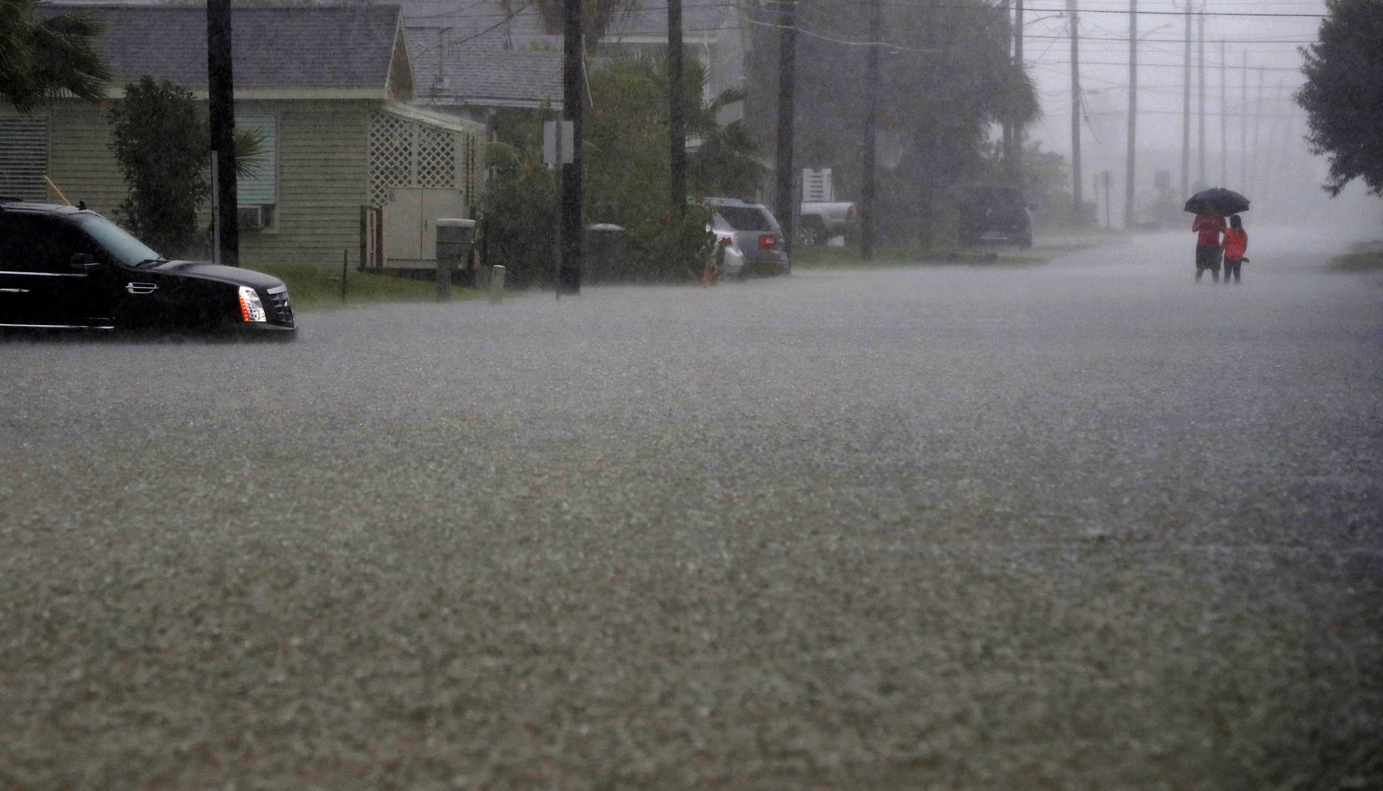 Una pareja vadea en aguas altas en la calle 59 cerca de la avenida S en Galveston, Texas, el miércoles 18 de septiembre de 2019, cuando las fuertes lluvias de la depresión tropical Imelda causaron inundaciones en las calles de la isla. 