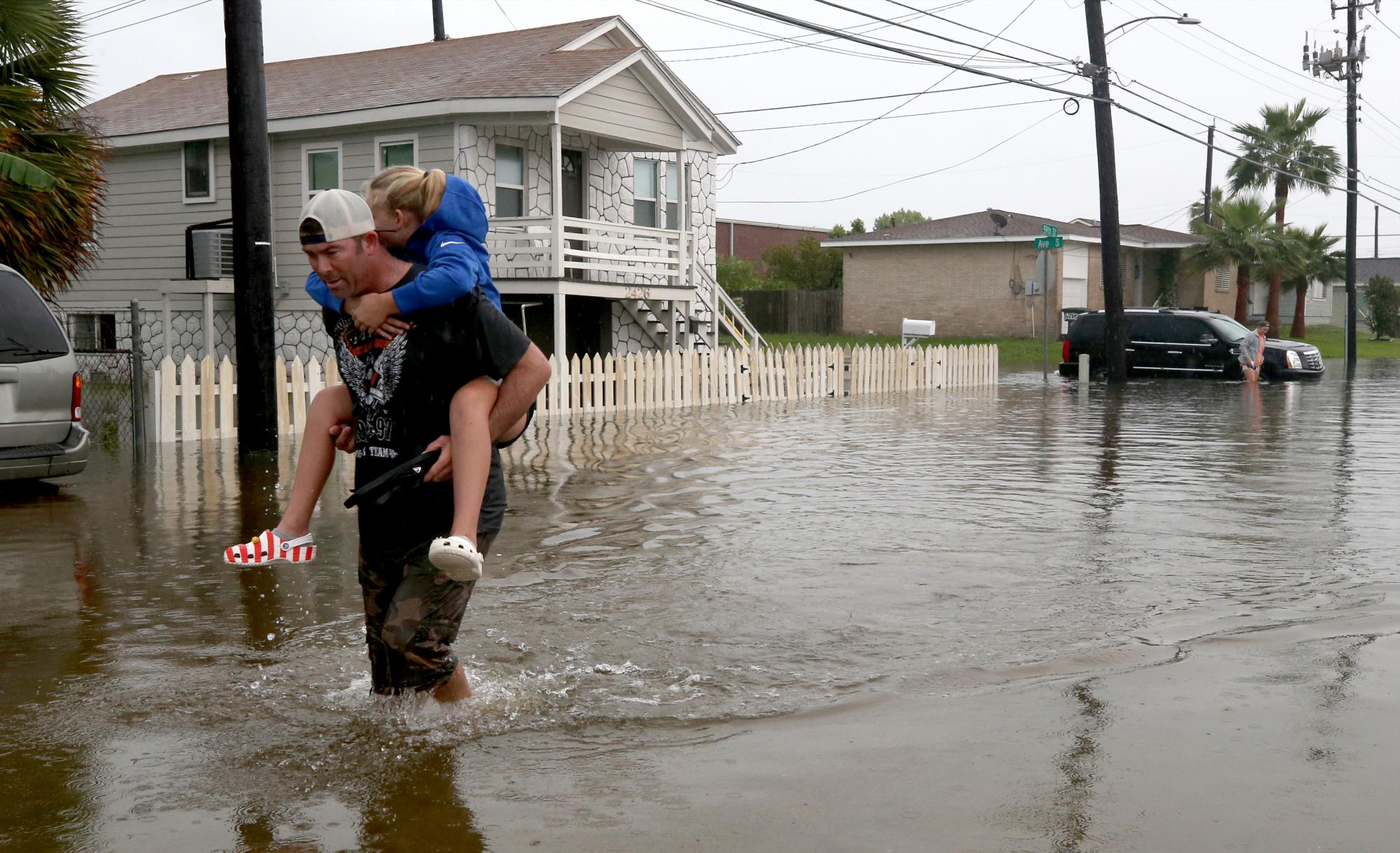 Terry Spencer lleva a su hija, Trinity, por aguas altas en la calle 59 cerca de Stewart Road en Galveston, Texas, el miércoles 18 de septiembre de 2019, cuando las fuertes lluvias de la depresión tropical Imelda causaron inundaciones en las calles de la isla. 